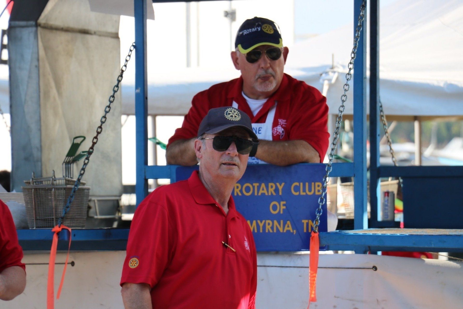Two men standing in front of a sign that says rotary club of myrna