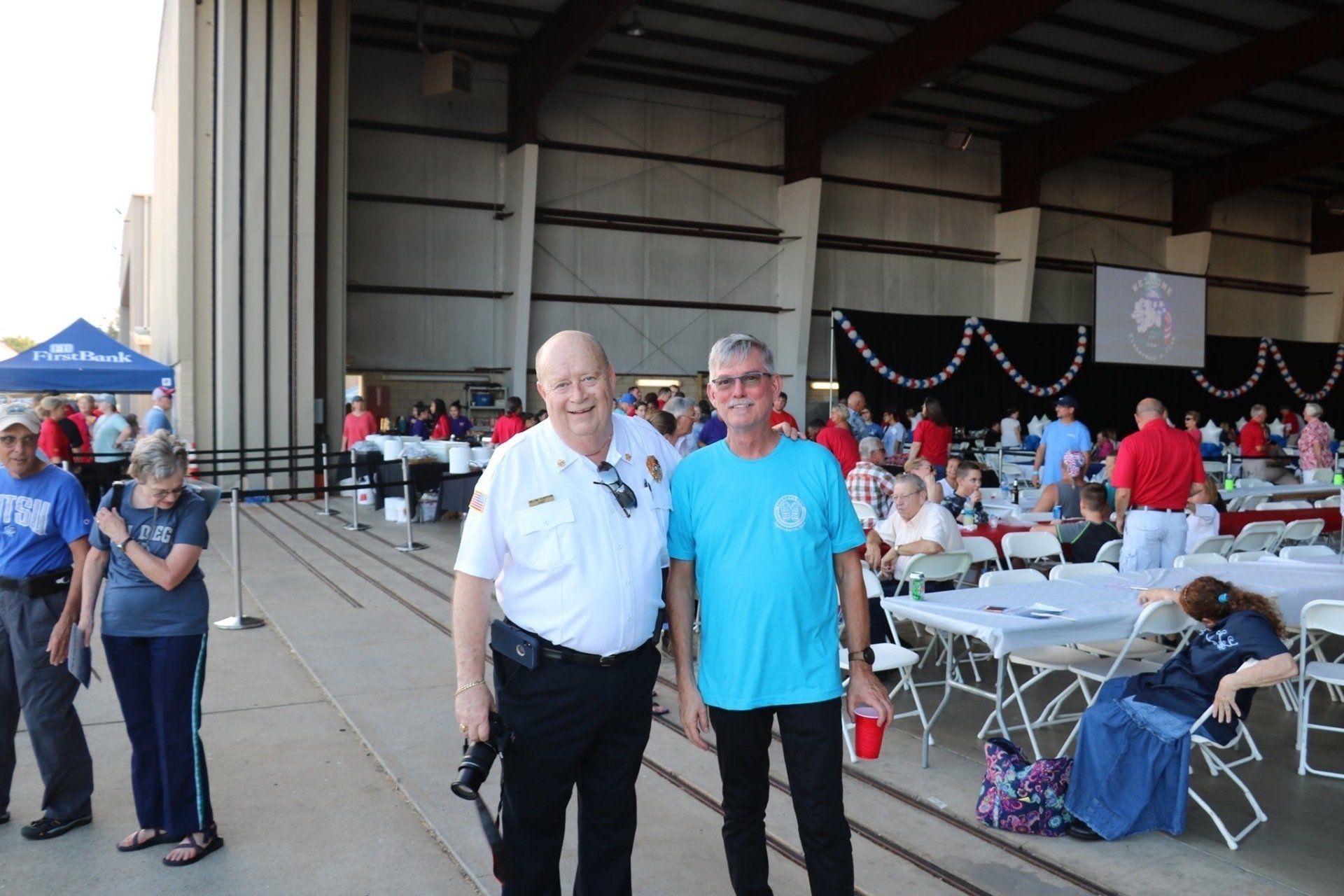 A police officer and a man in a blue shirt are posing for a picture.
