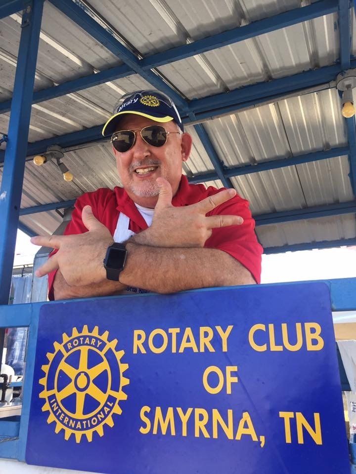 A man stands in front of a sign for the rotary club of smyrna tn