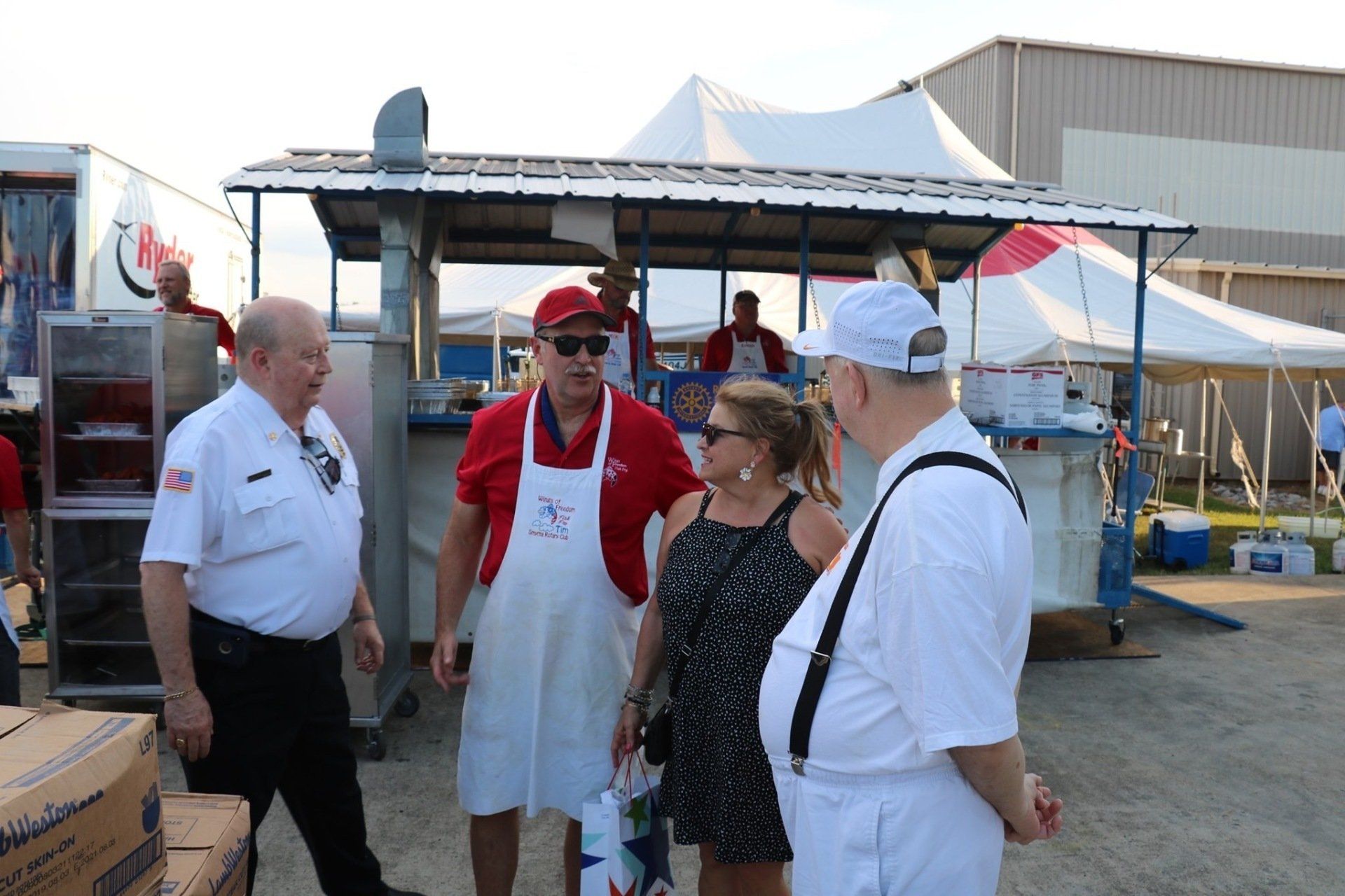 A group of people are standing in front of a food truck talking to each other.