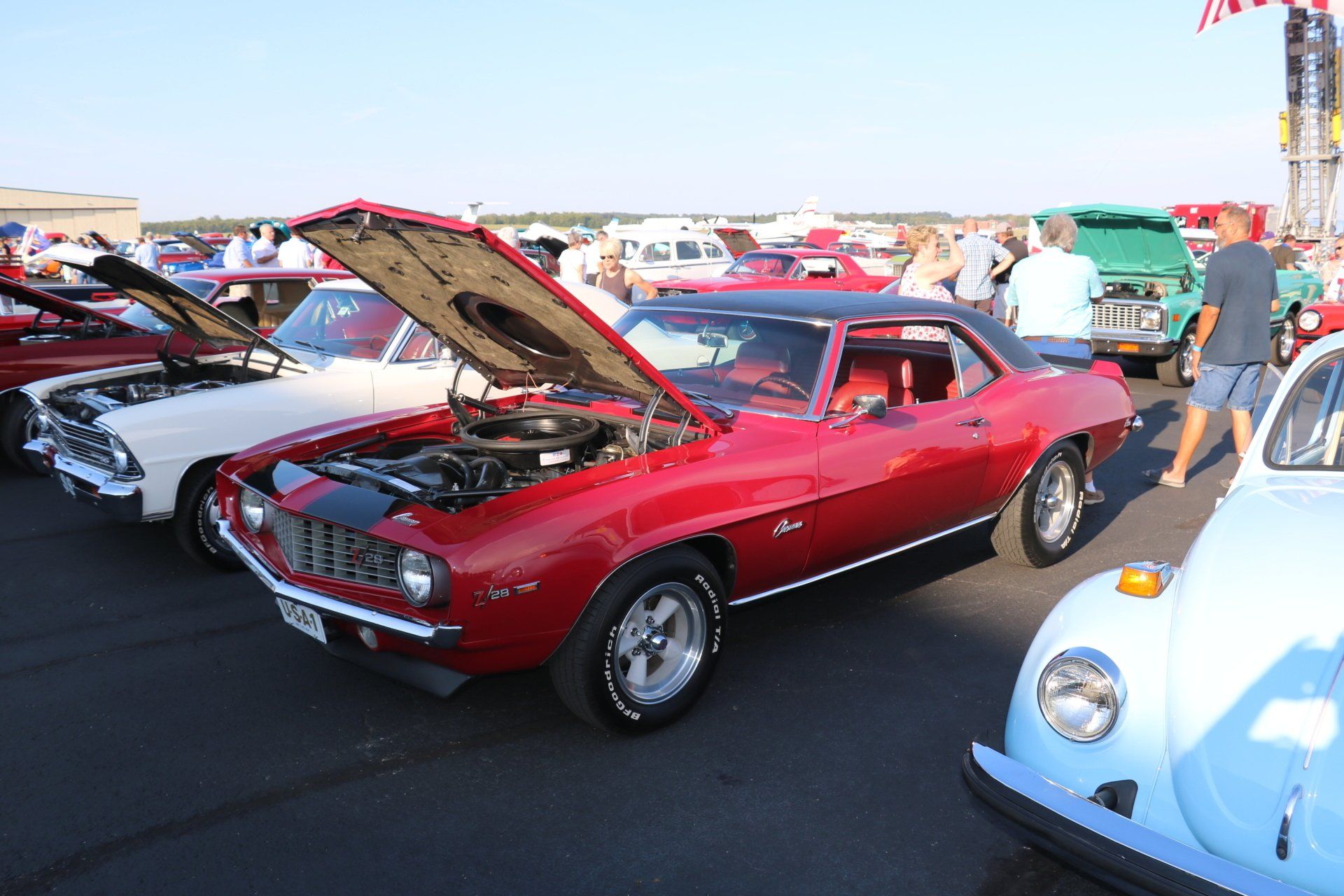 A red car with the hood up is parked next to a white car