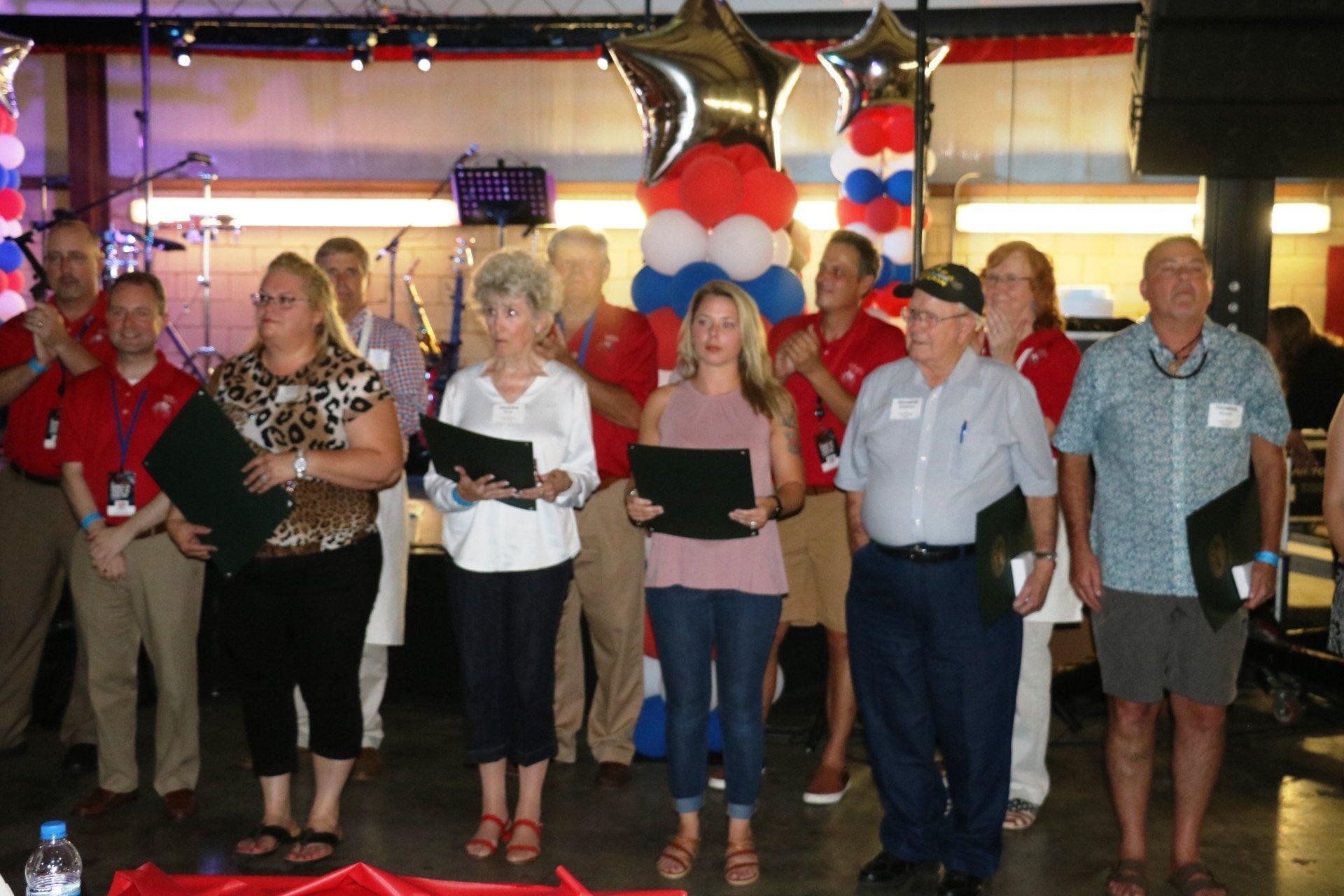 A group of people standing in front of balloons holding papers