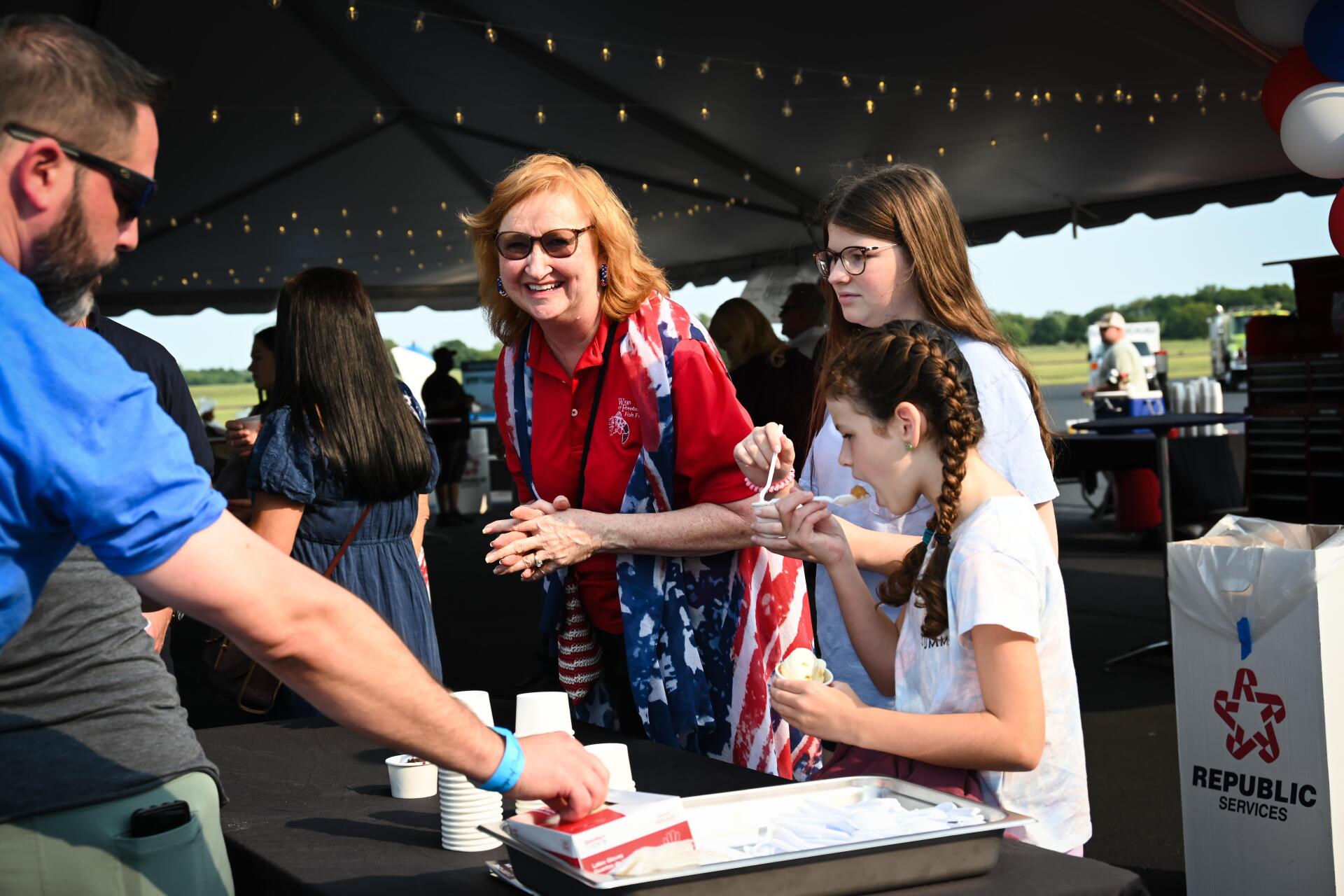 A group of people are standing around a table under a tent.
