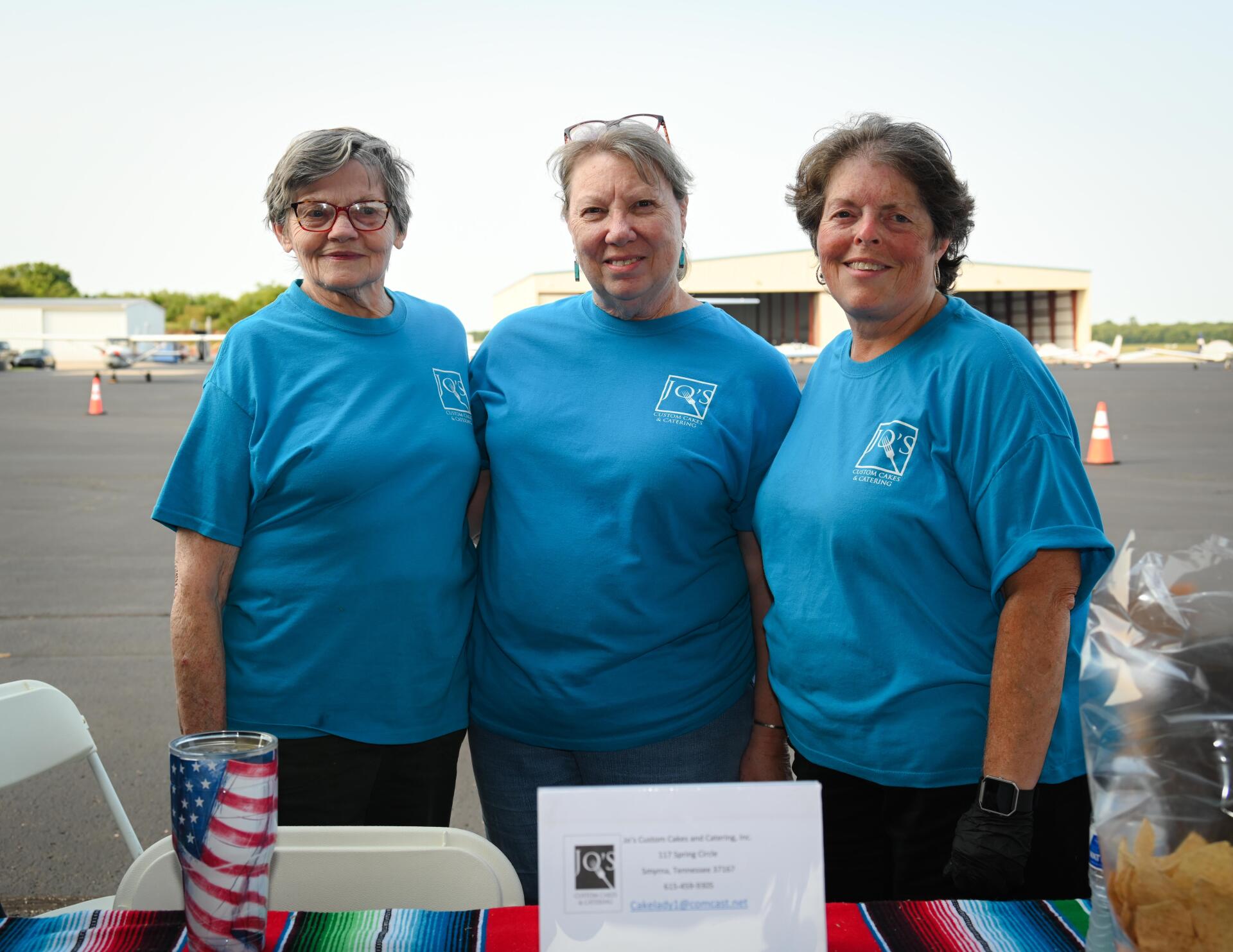 Three women wearing blue shirts are posing for a picture