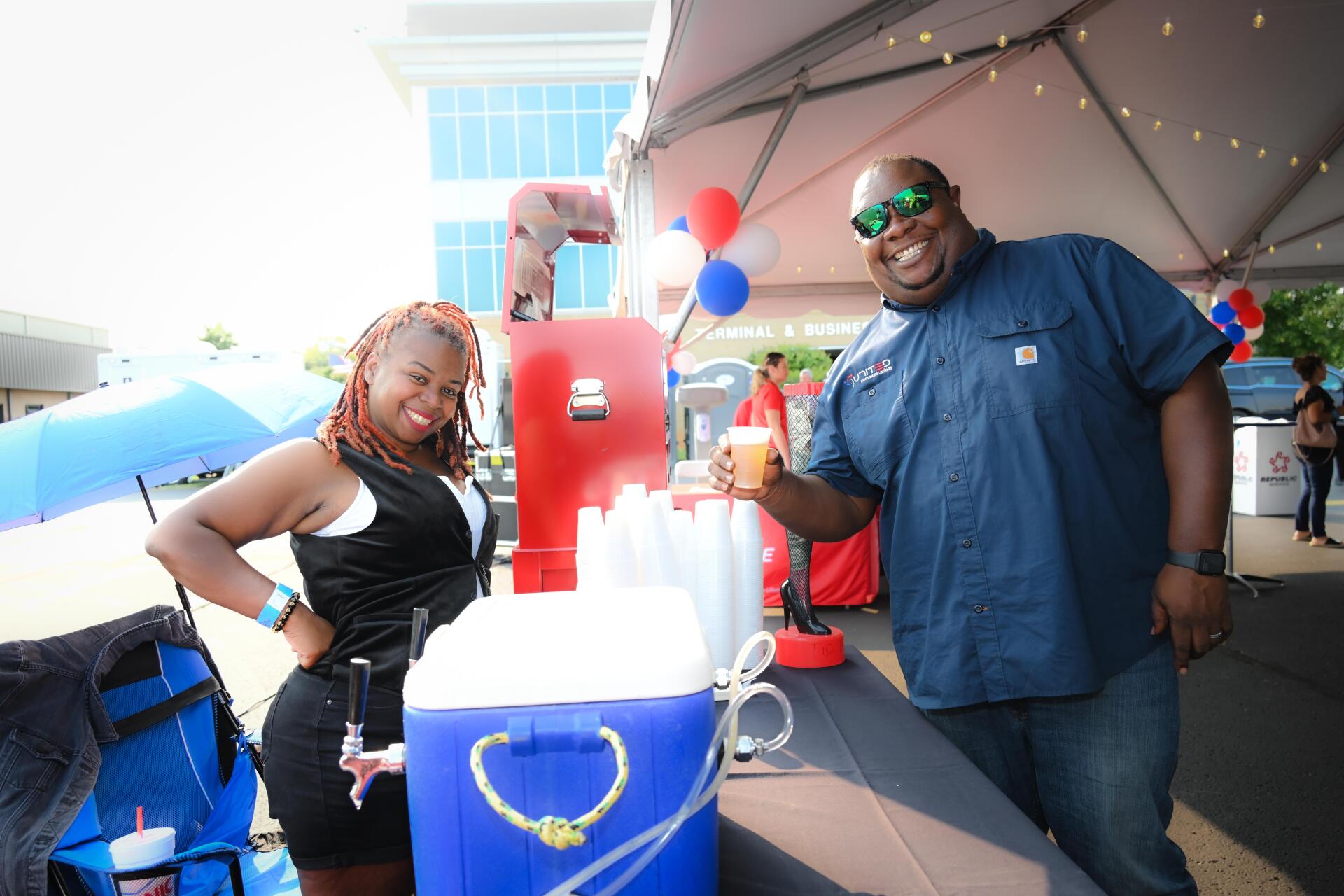 A man and a woman are standing next to a cooler.