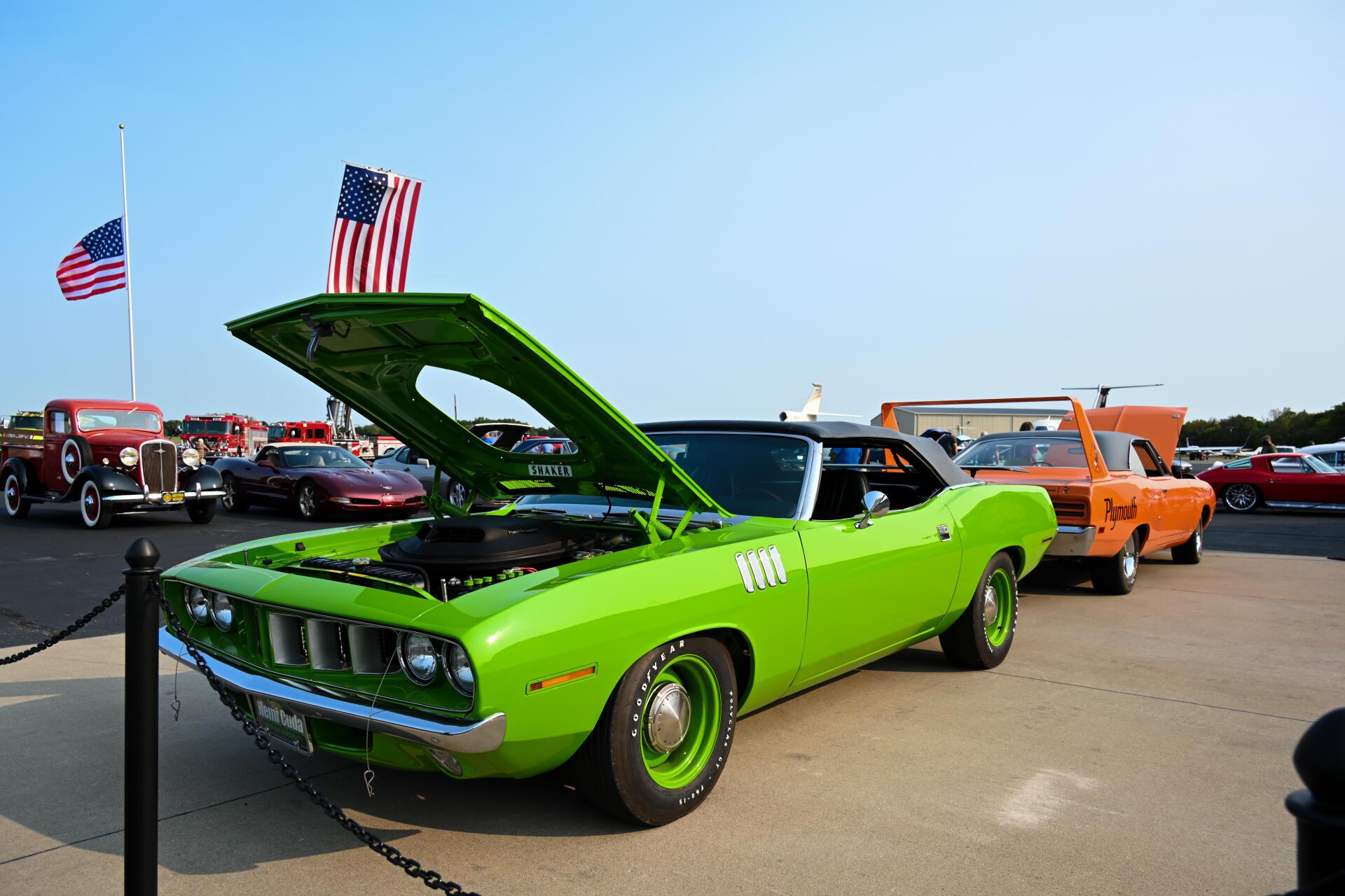 A green car with the hood up is parked in a parking lot