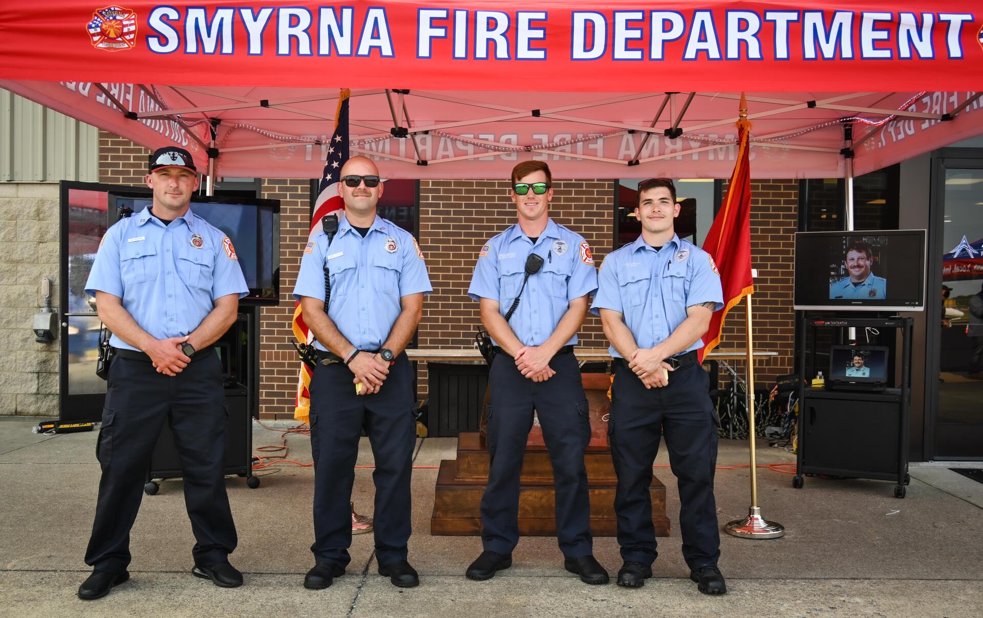 A group of firefighters standing in front of a sign for the smyrna fire department