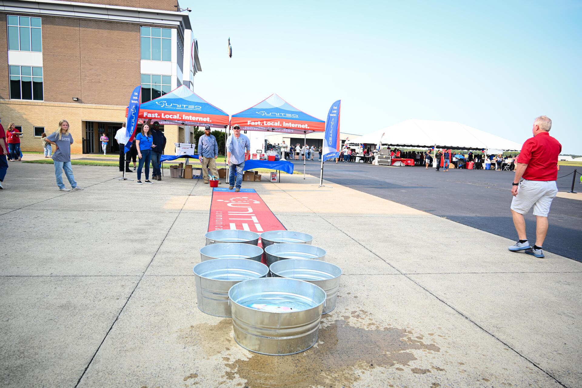 A group of people are playing a game of beer pong on a sidewalk.