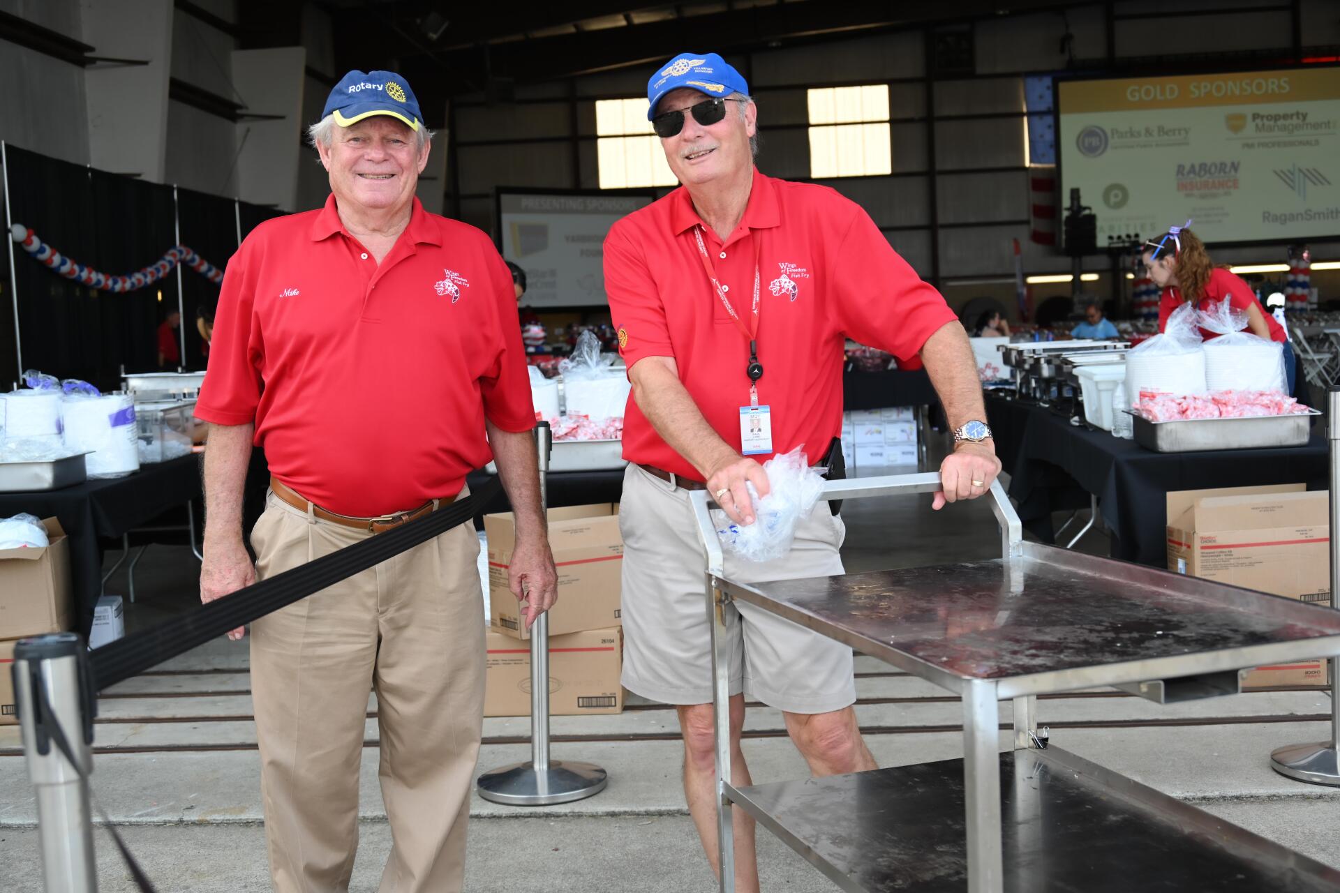Two men in red shirts are standing next to each other