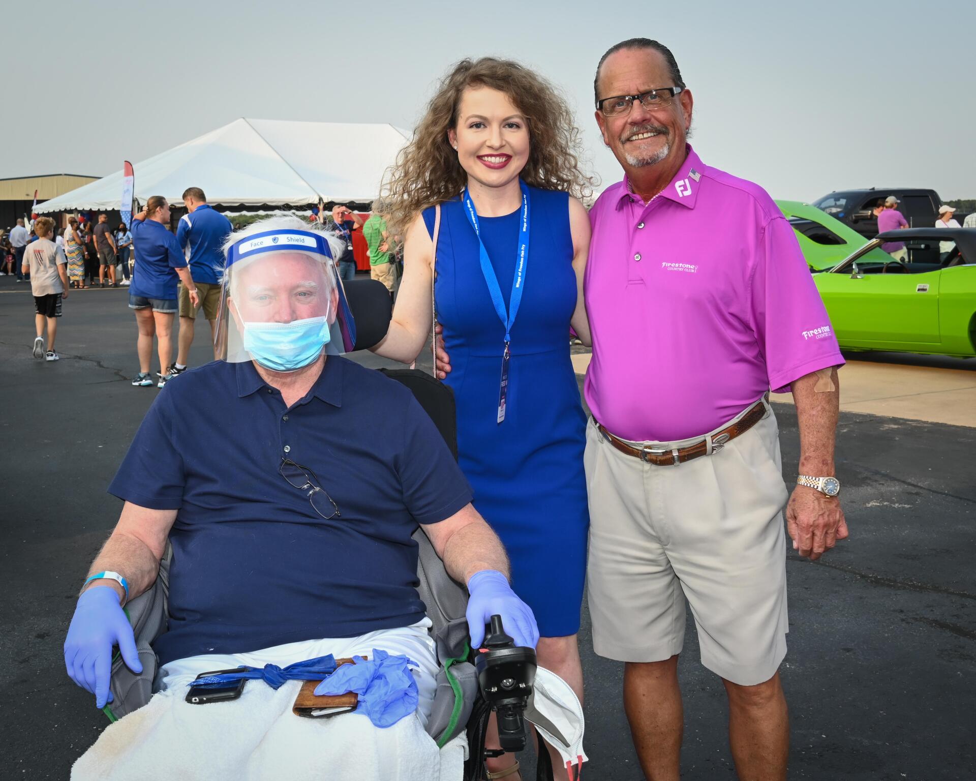 A man in a wheelchair is posing for a picture with two people.
