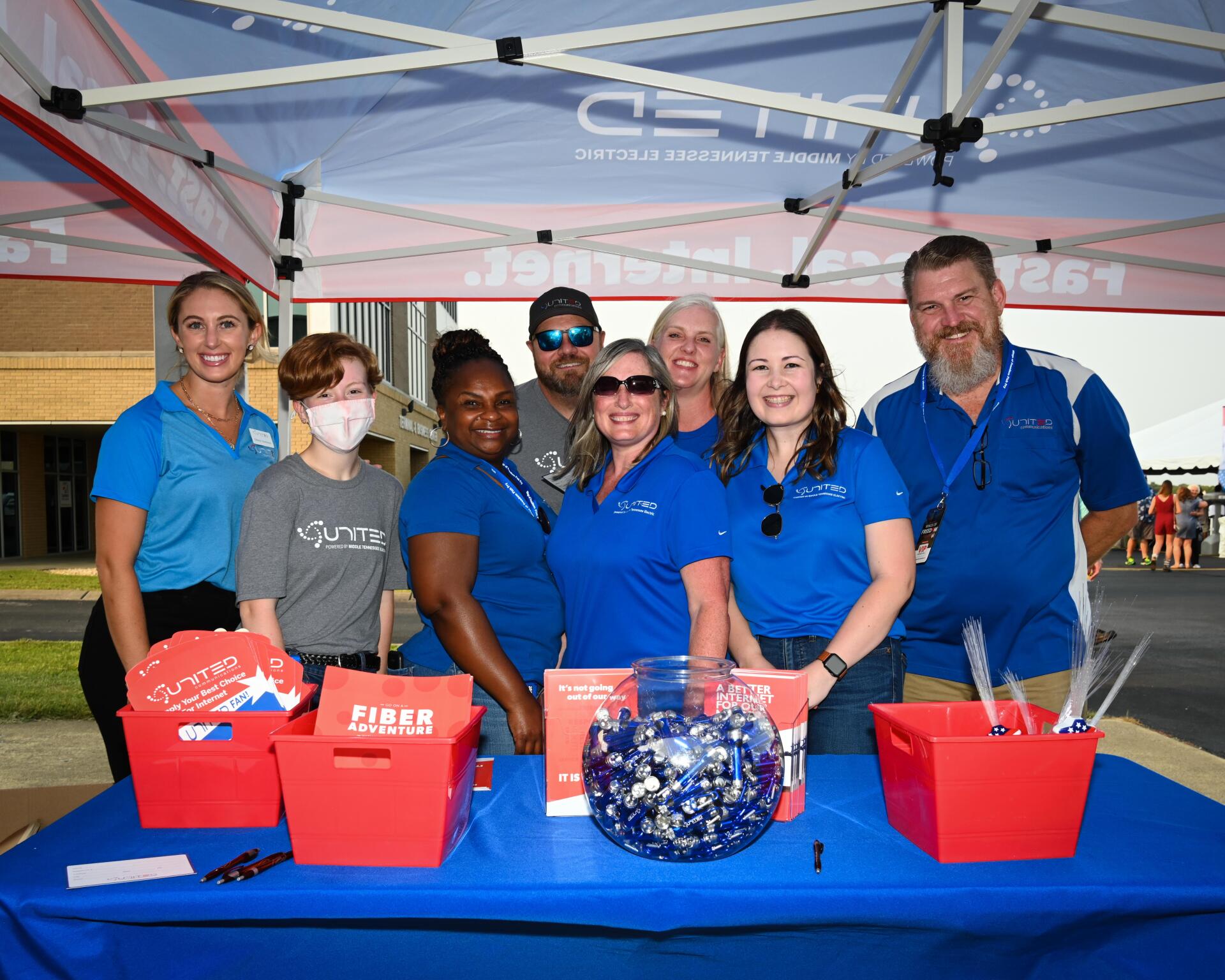 A group of people standing around a table under a tent.