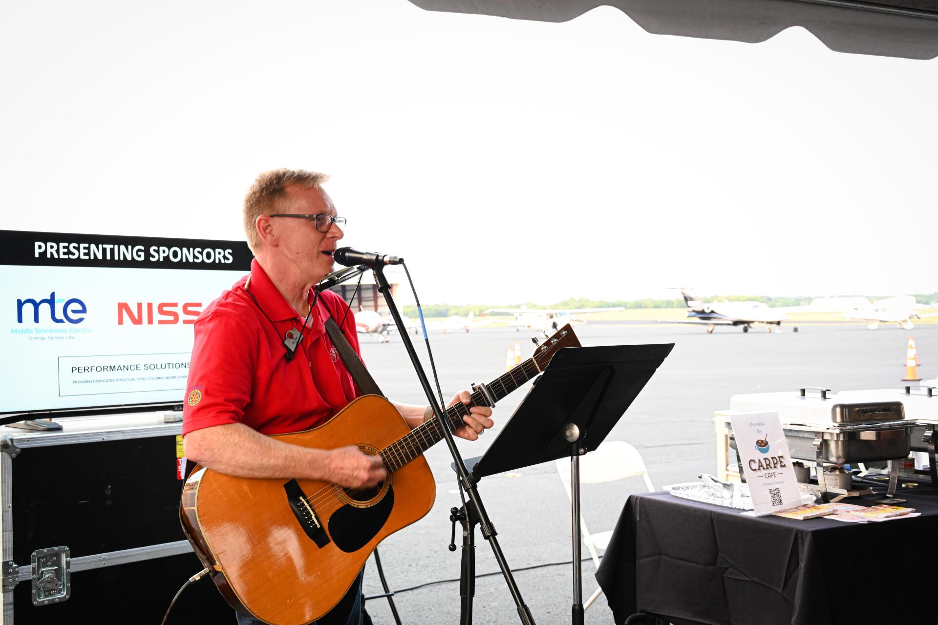 A man is playing a guitar and singing into a microphone.