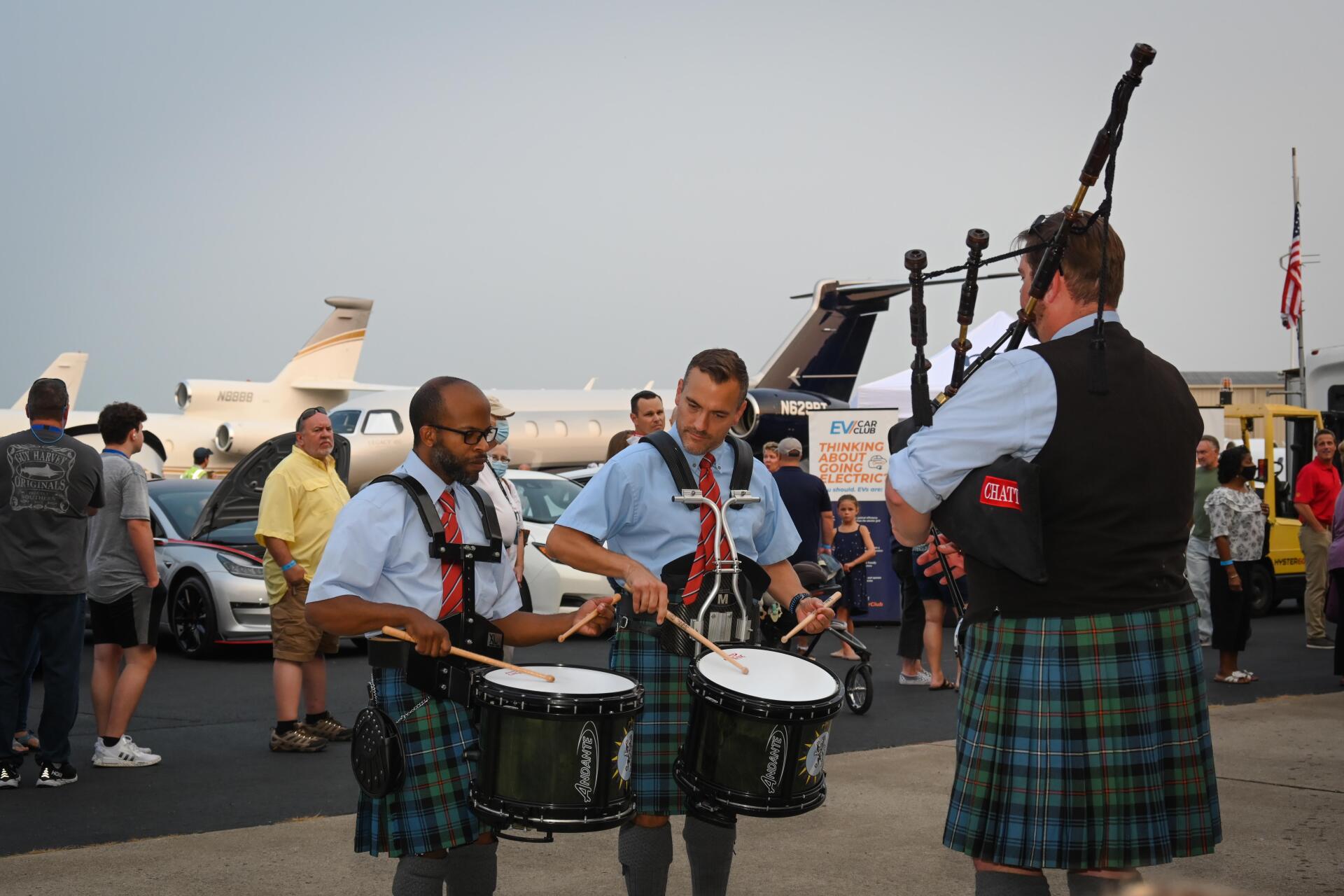 A group of men in kilts are playing drums and bagpipes