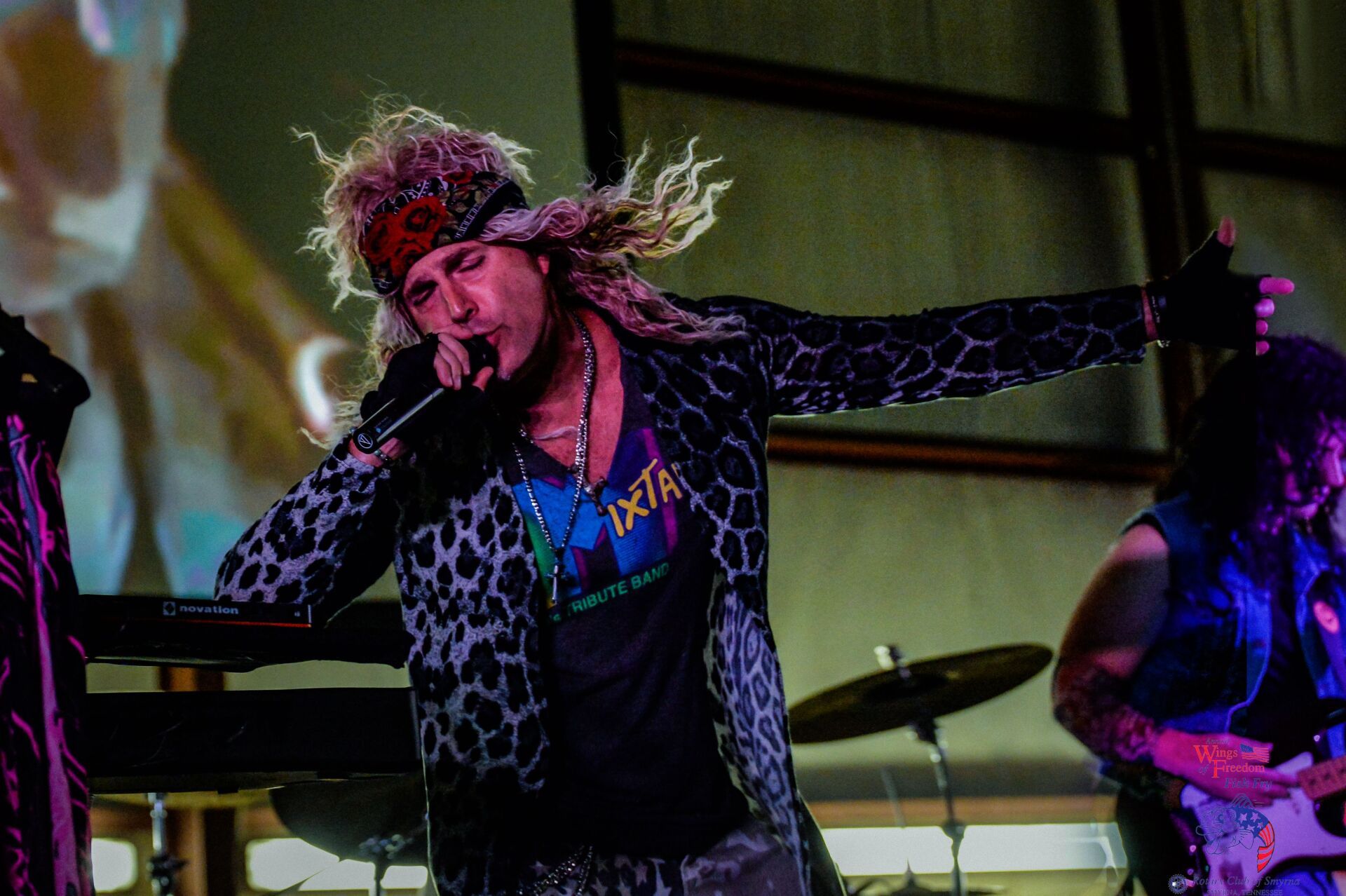 A man is singing into a microphone while another man plays a guitar.