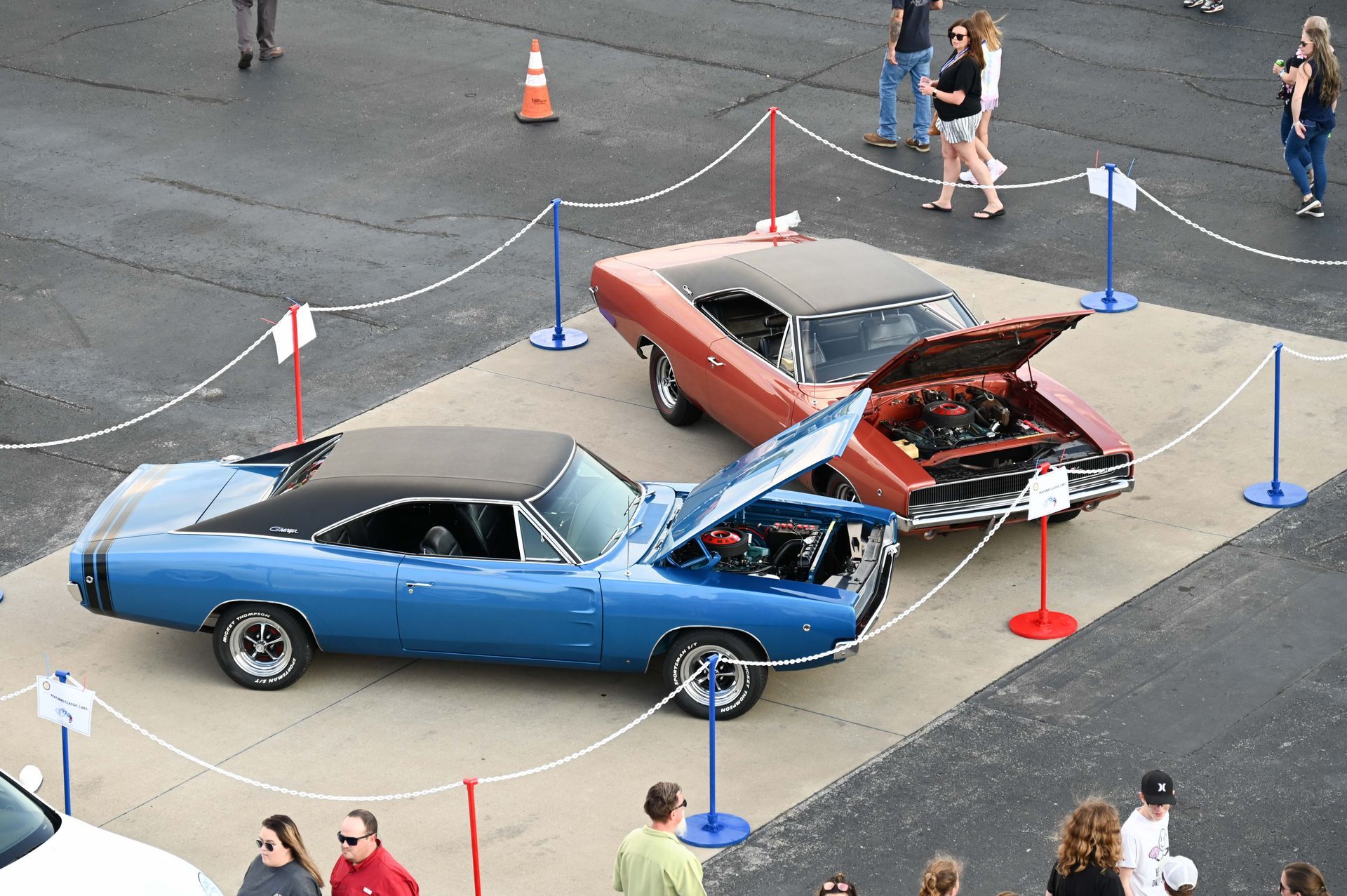 A group of people are standing around a parking lot with cars on display