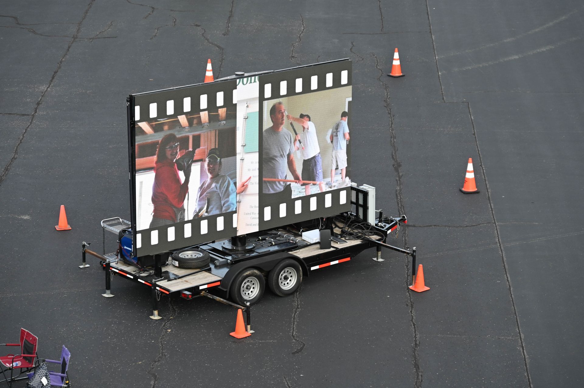 A trailer with a large screen on it is surrounded by traffic cones.