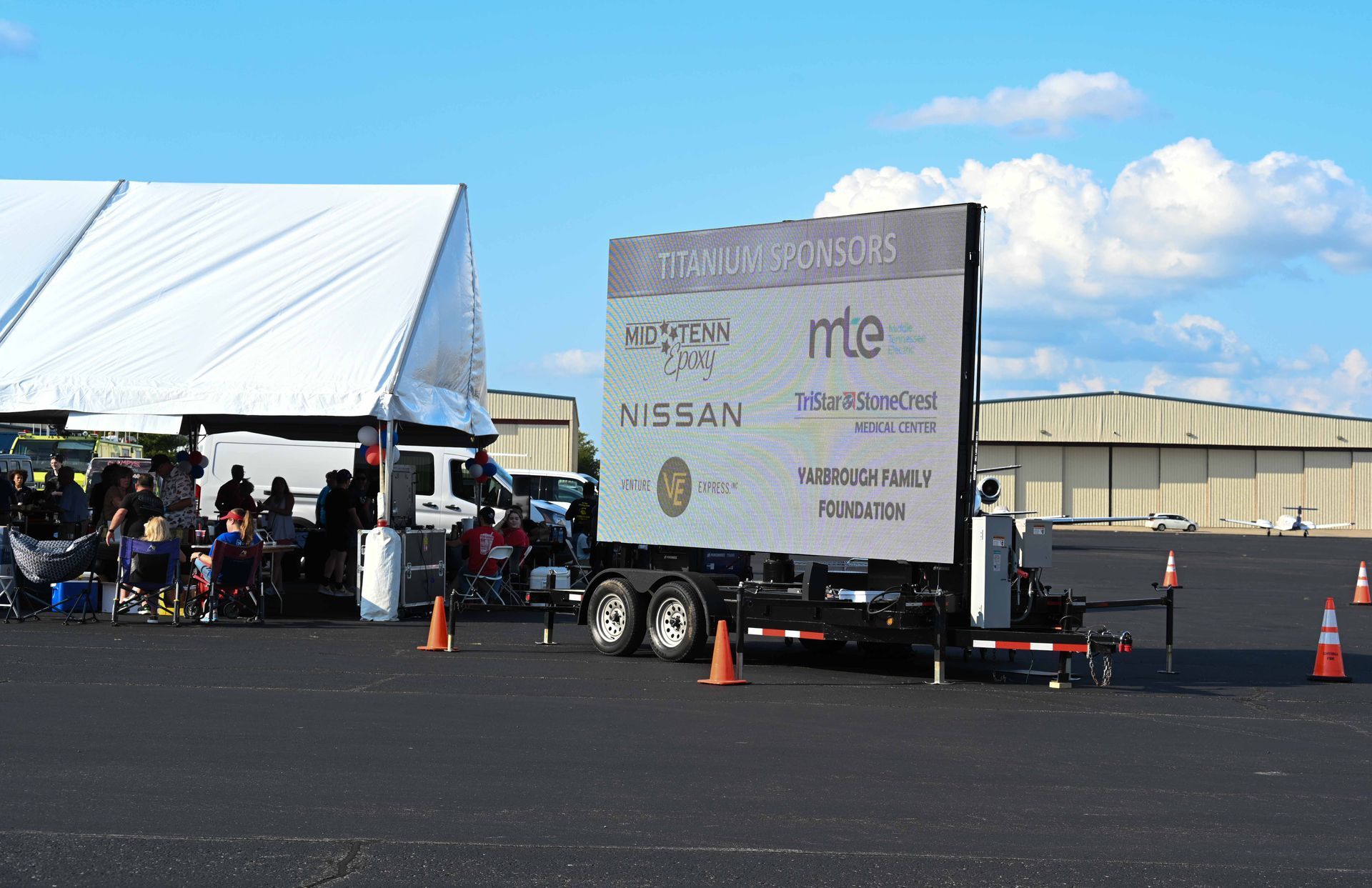 A nissan trailer is parked in a parking lot next to a tent.
