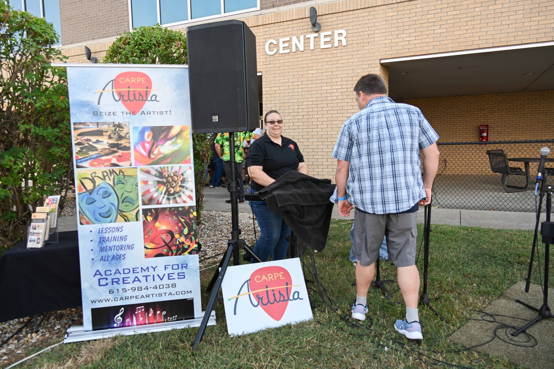 A man and a woman are standing in front of a sign that says center.