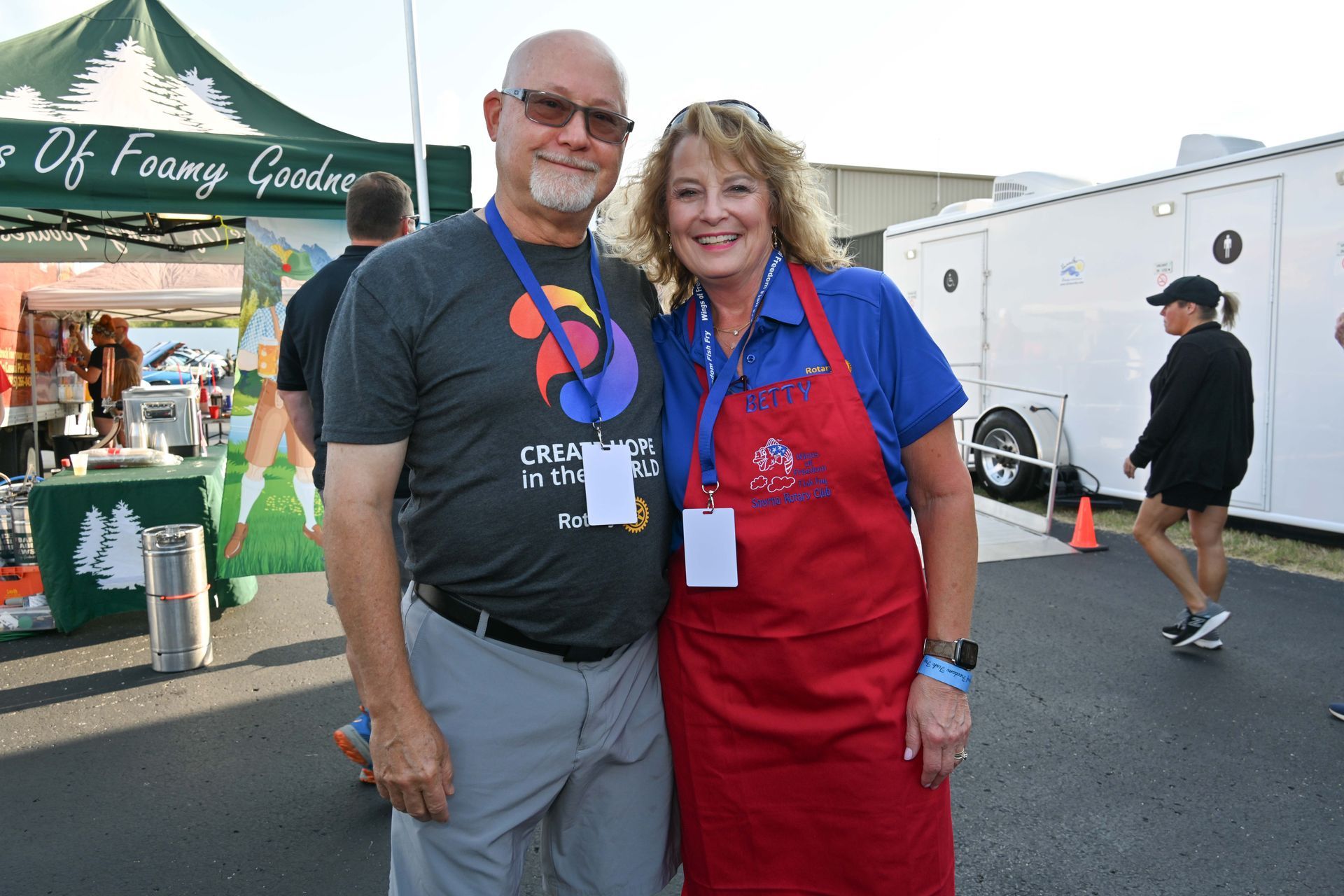 A man and a woman are posing for a picture in front of a tent.