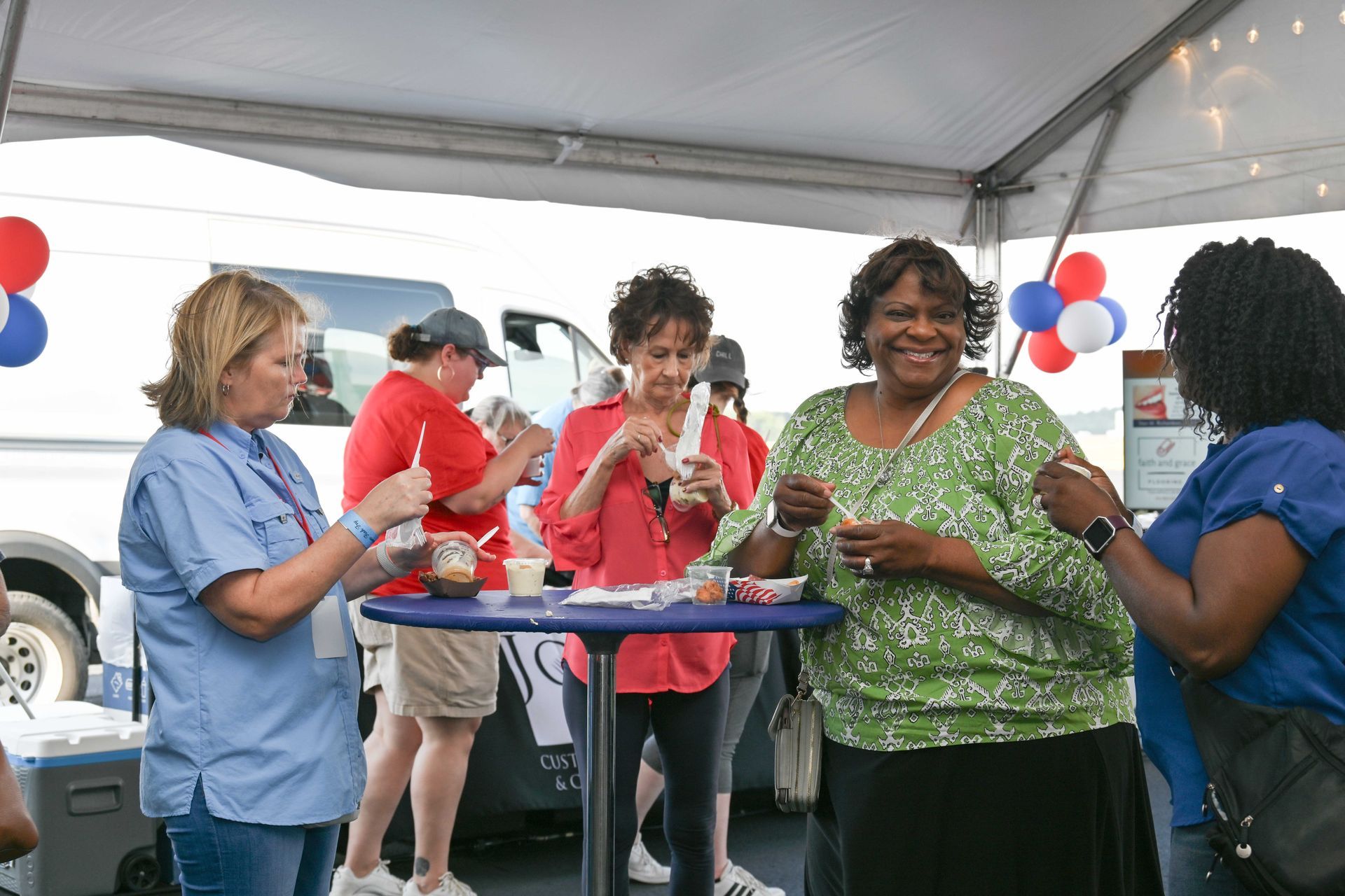 A group of women are standing under a tent eating food