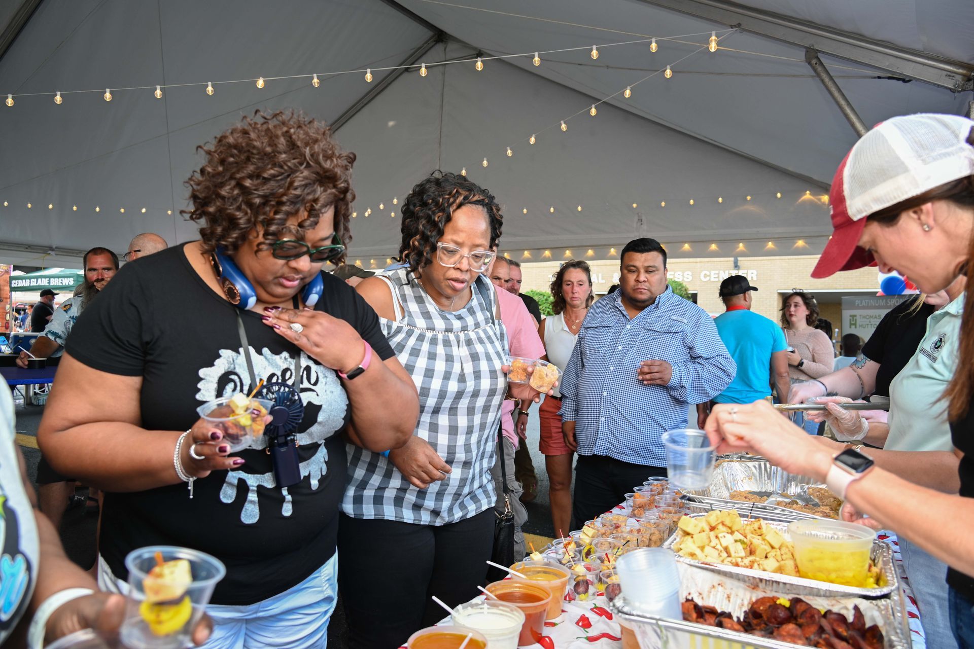 A group of people are standing around a table eating food.