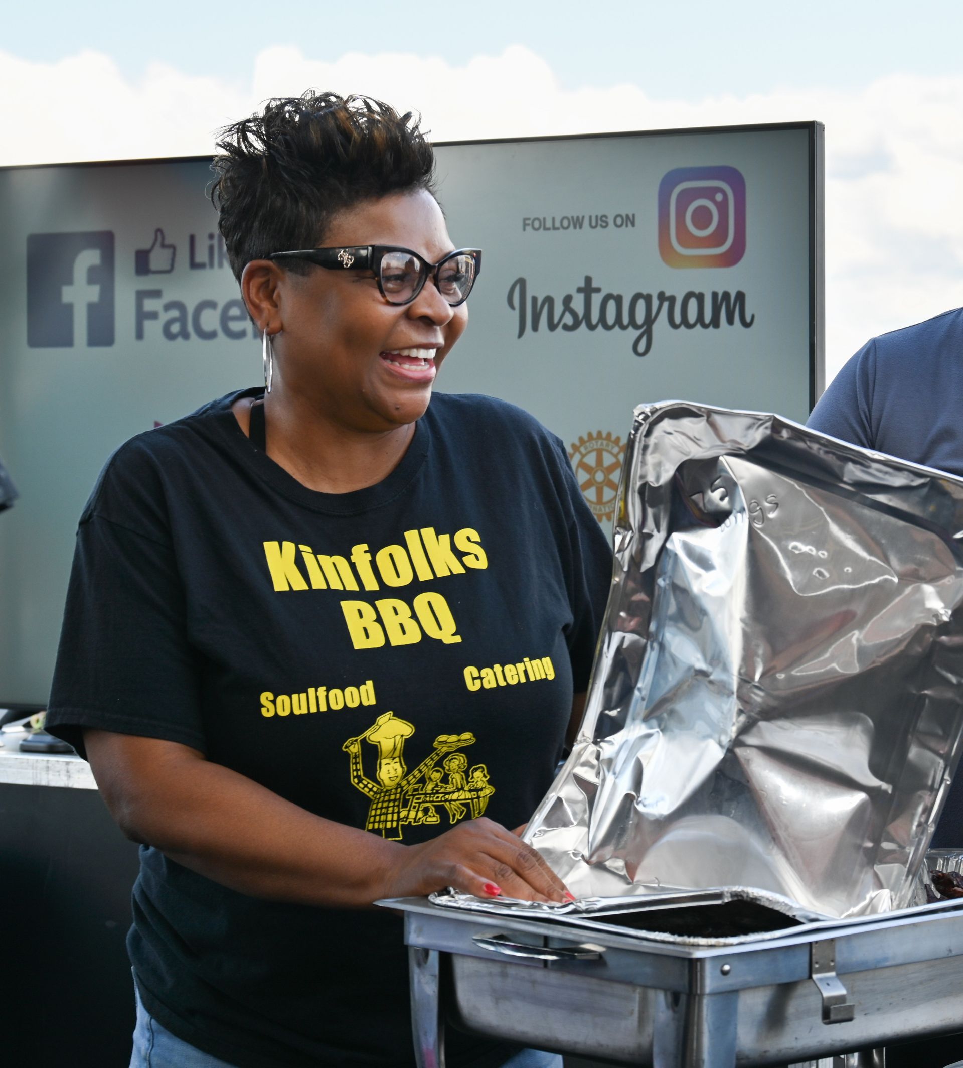 A woman wearing a shirt that says kinfolk 's bbq