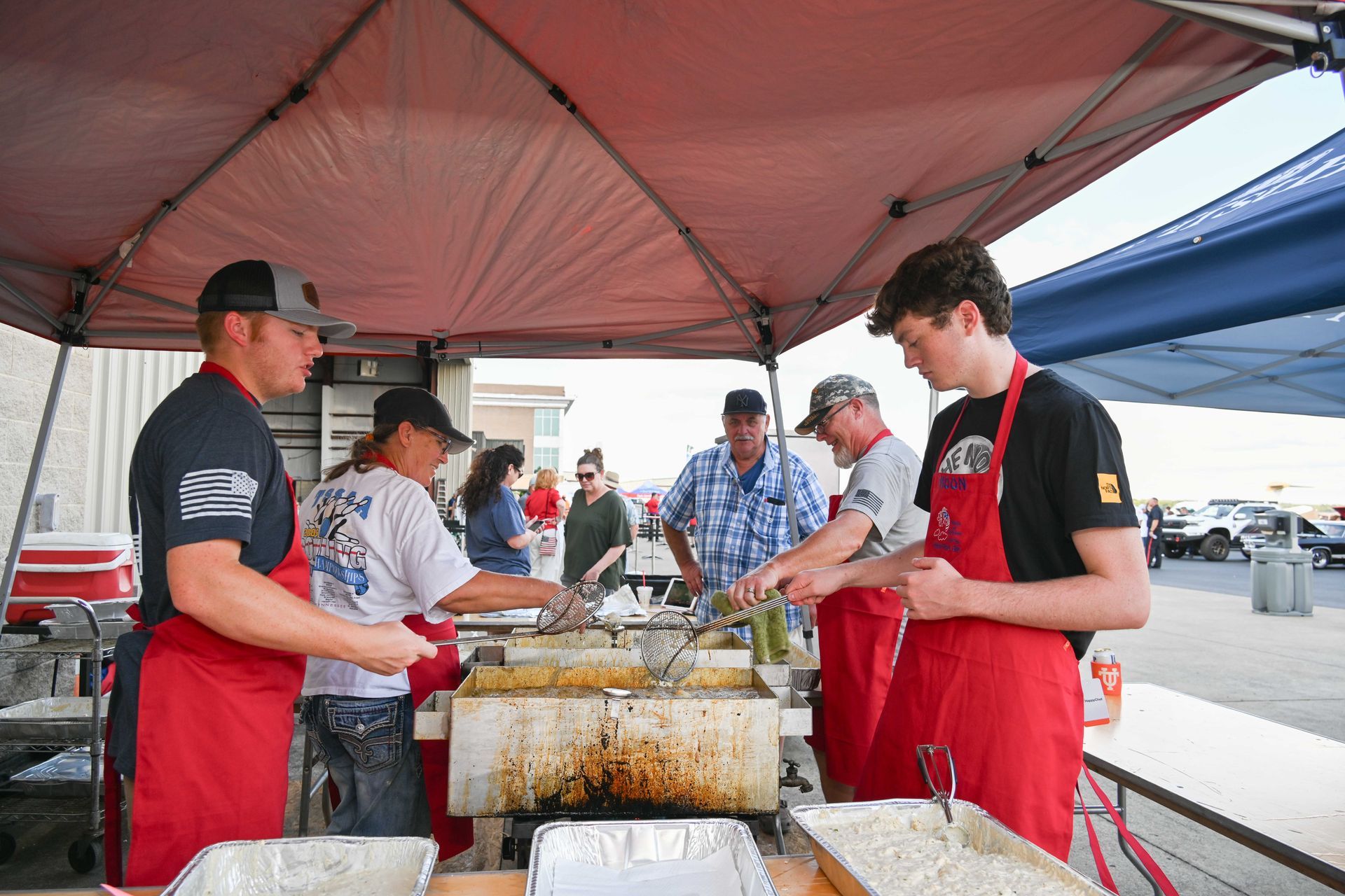 A group of people are cooking food under a tent.