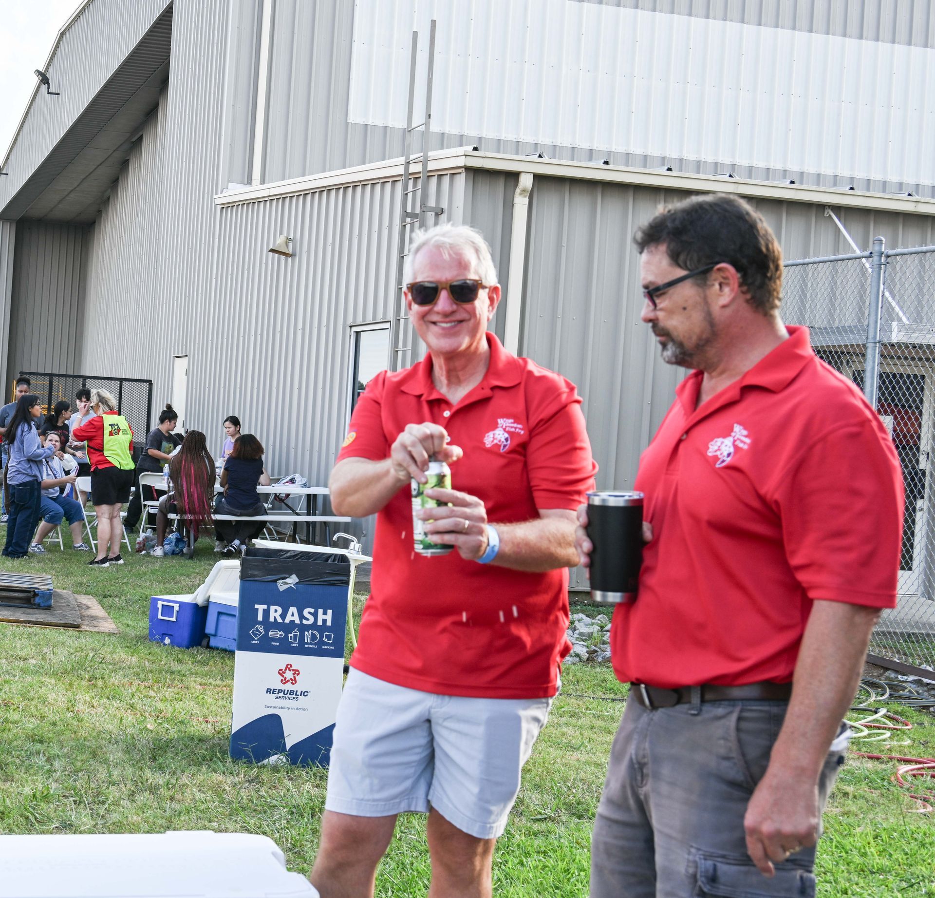 Two men standing in front of a trash can