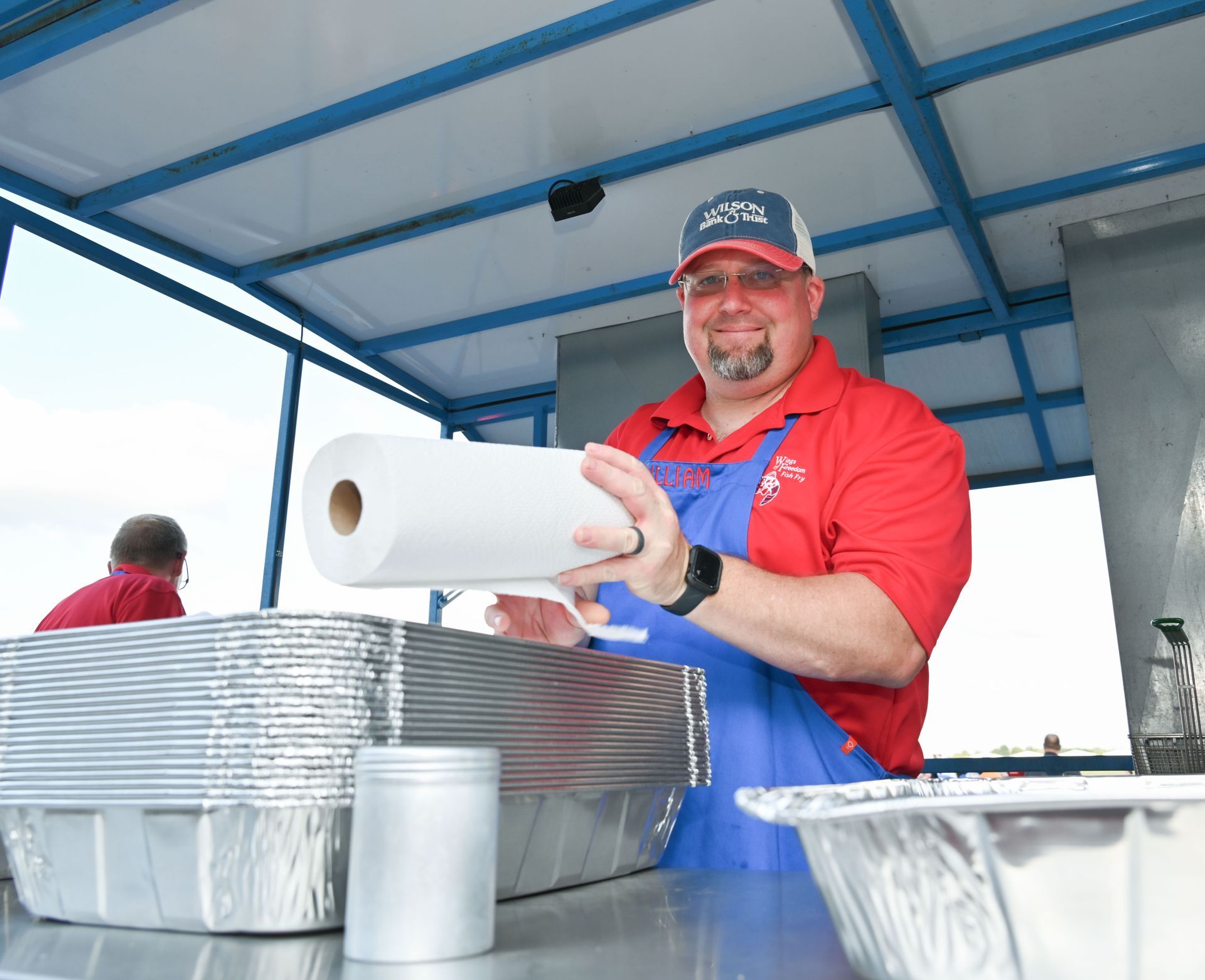 A man in a red shirt is holding a roll of paper towels