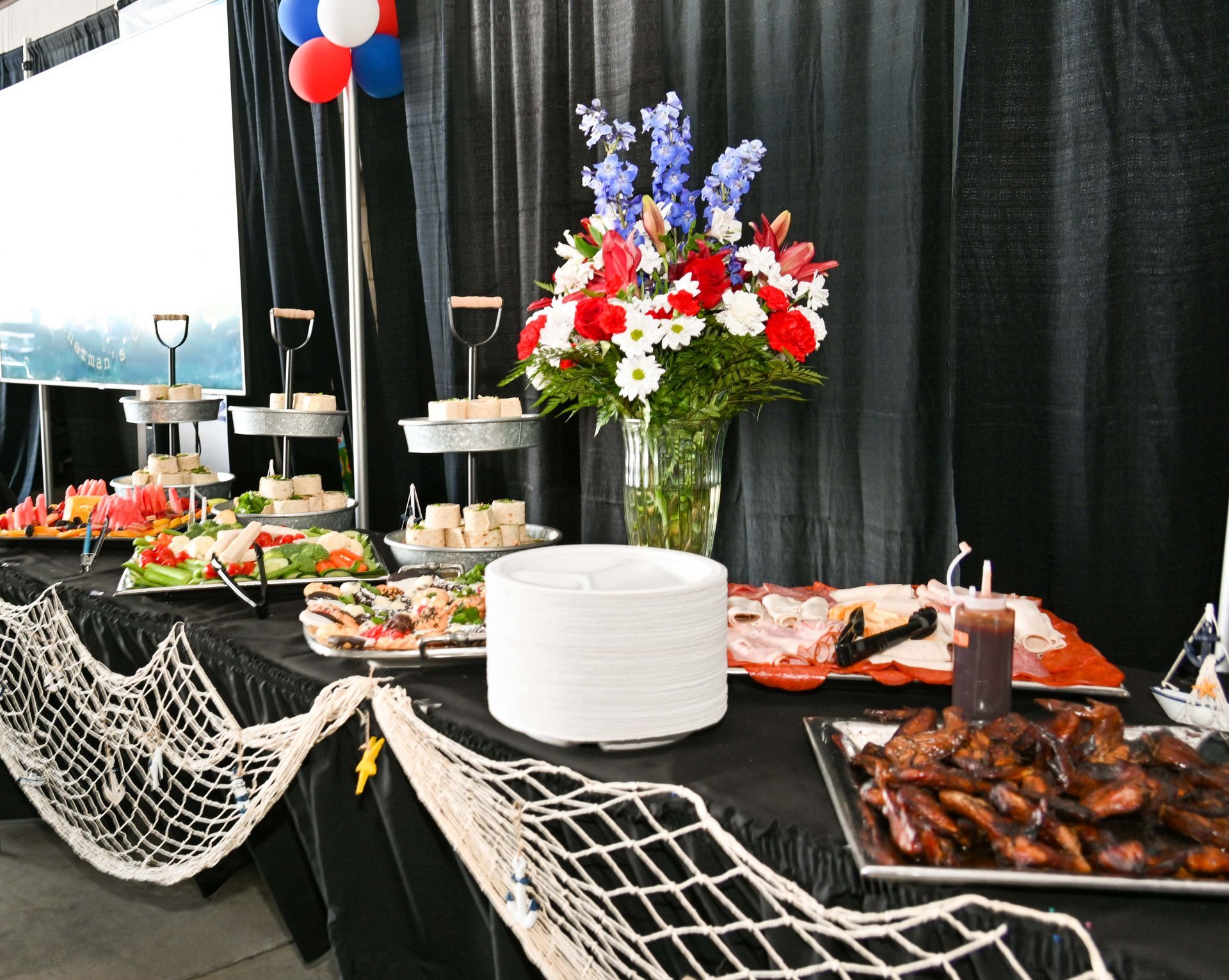 A buffet table with plates of food and a vase of flowers