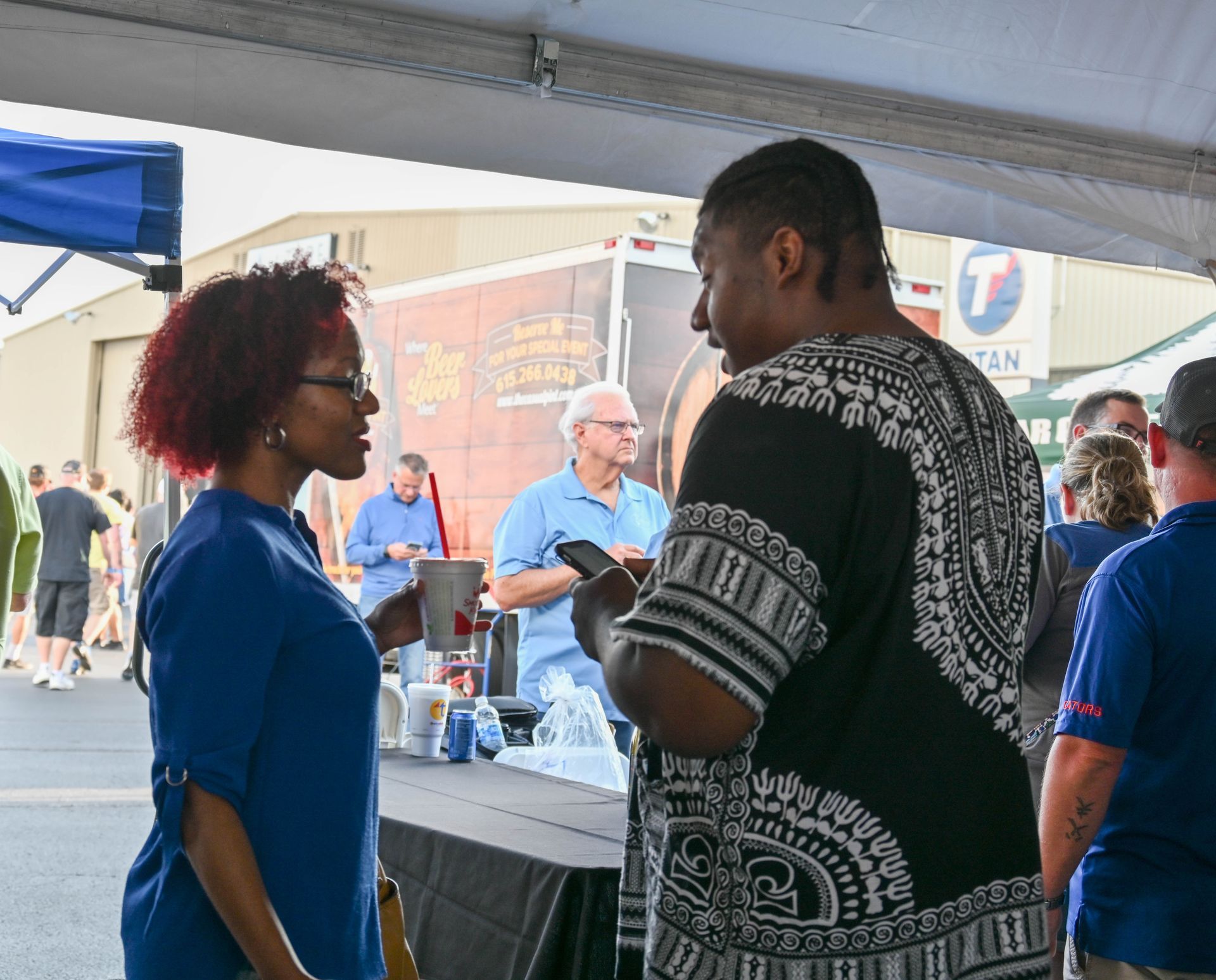 A woman in a blue shirt is talking to a man in a black shirt