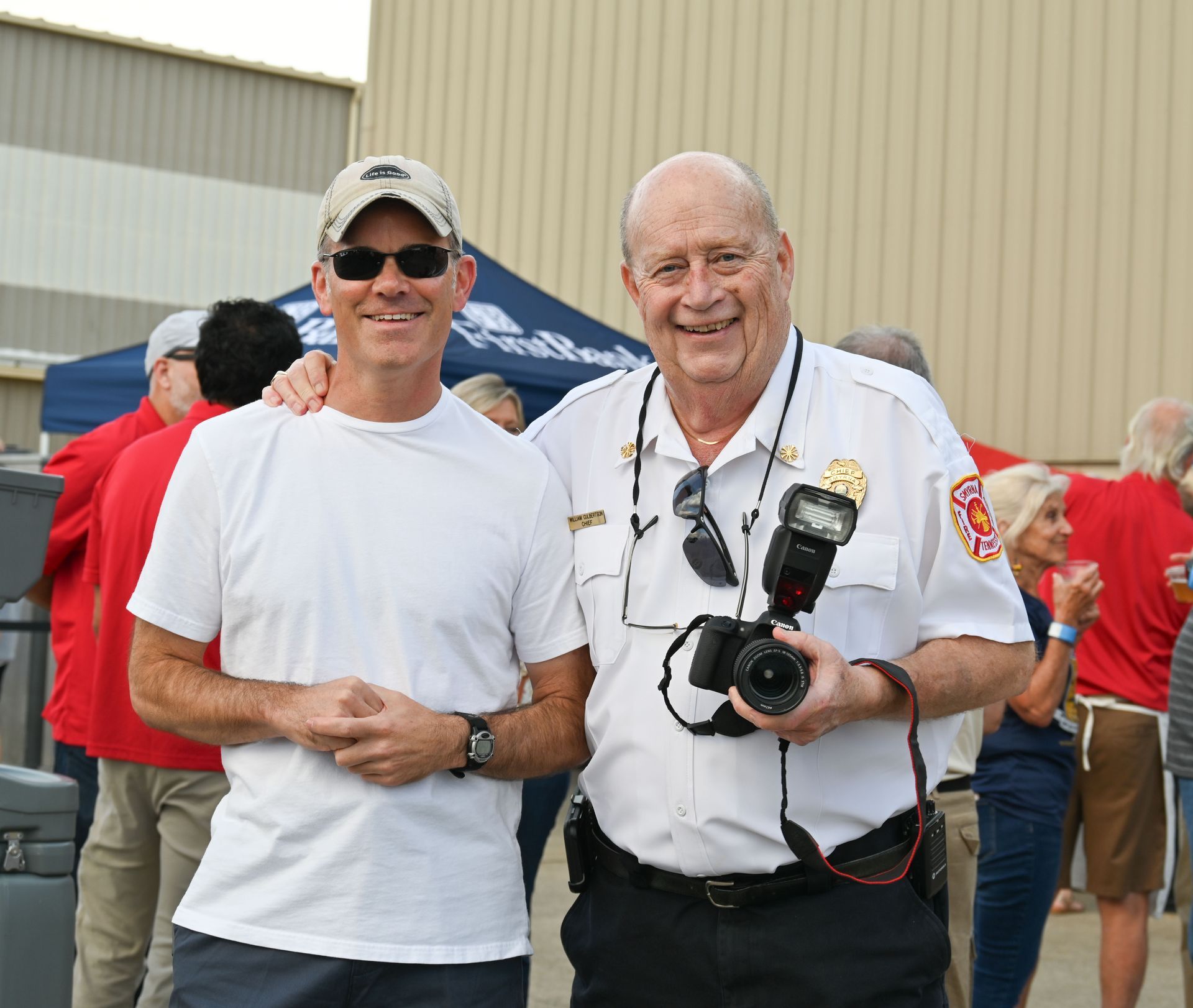 Two men posing for a picture with one holding a camera