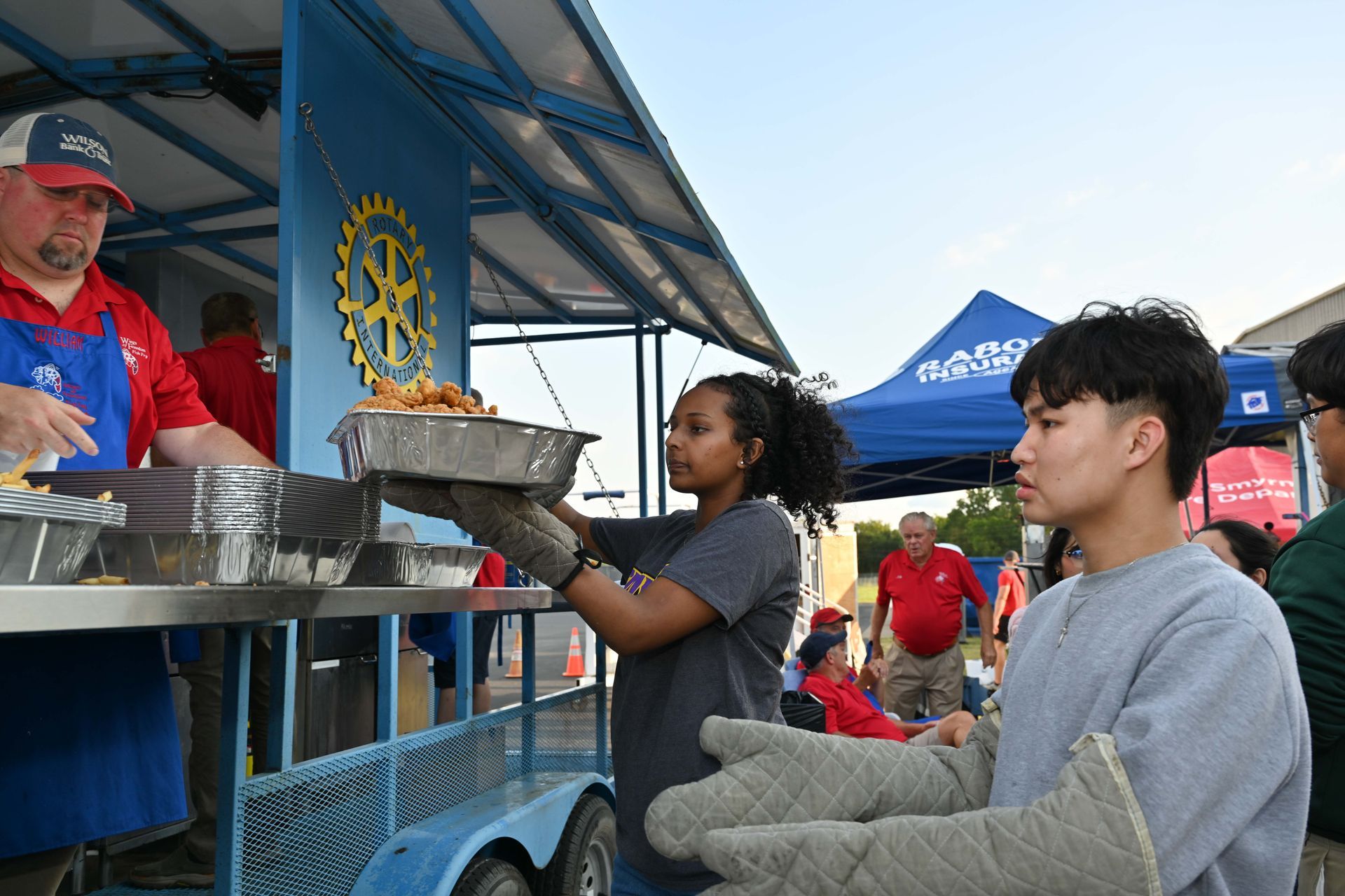 A man and a woman are serving food from a food truck.