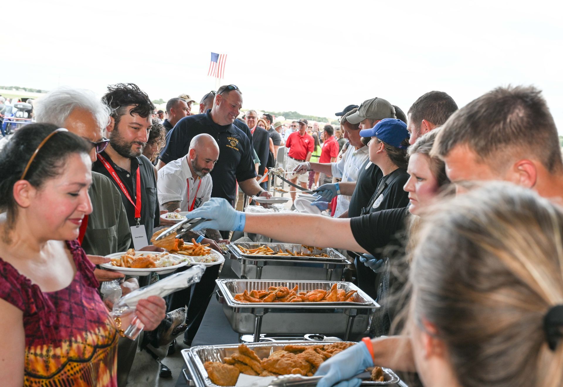 A group of people are standing around a table eating food.