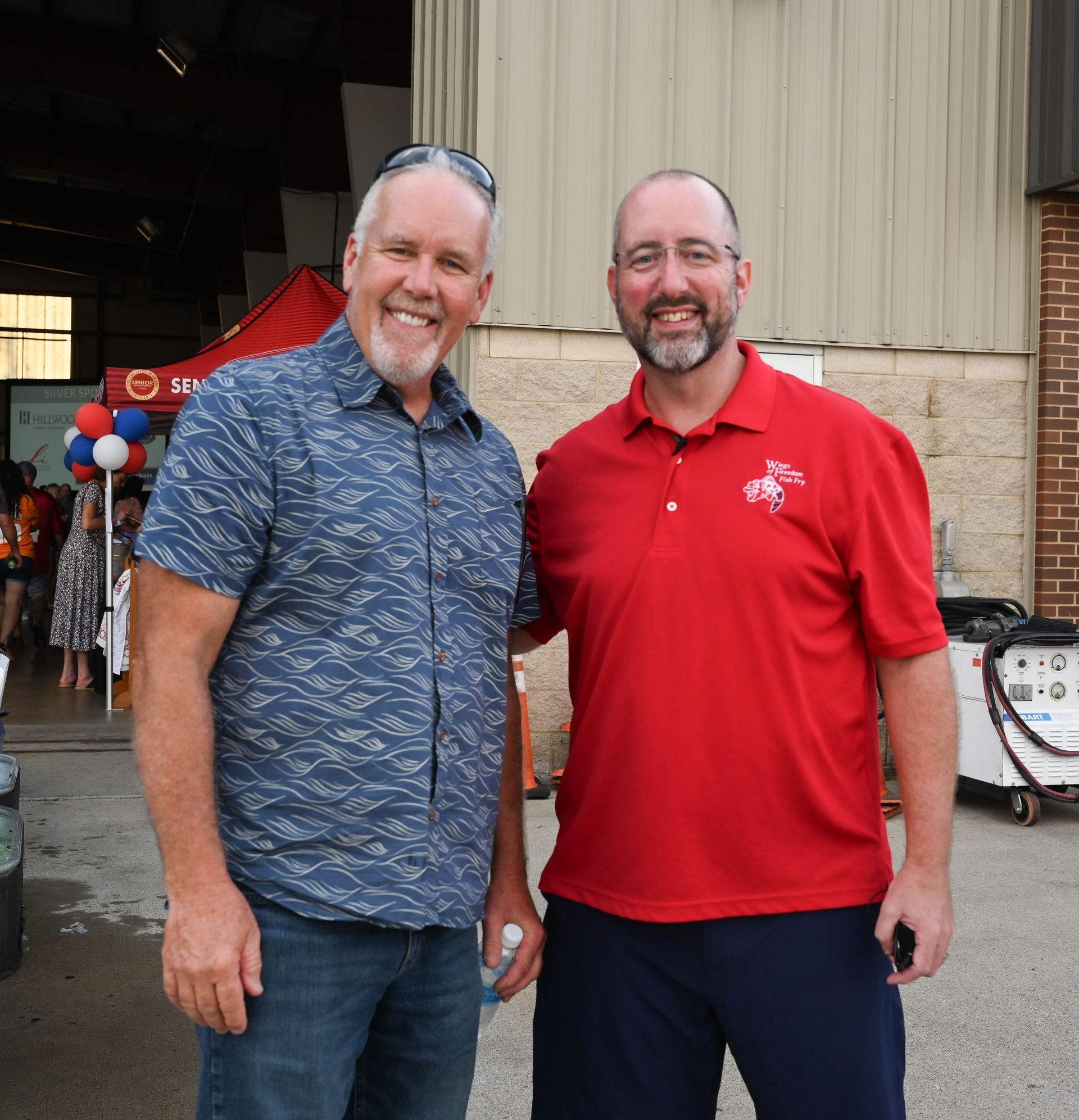 Two men posing for a picture with one wearing a red shirt with a bicycle on it