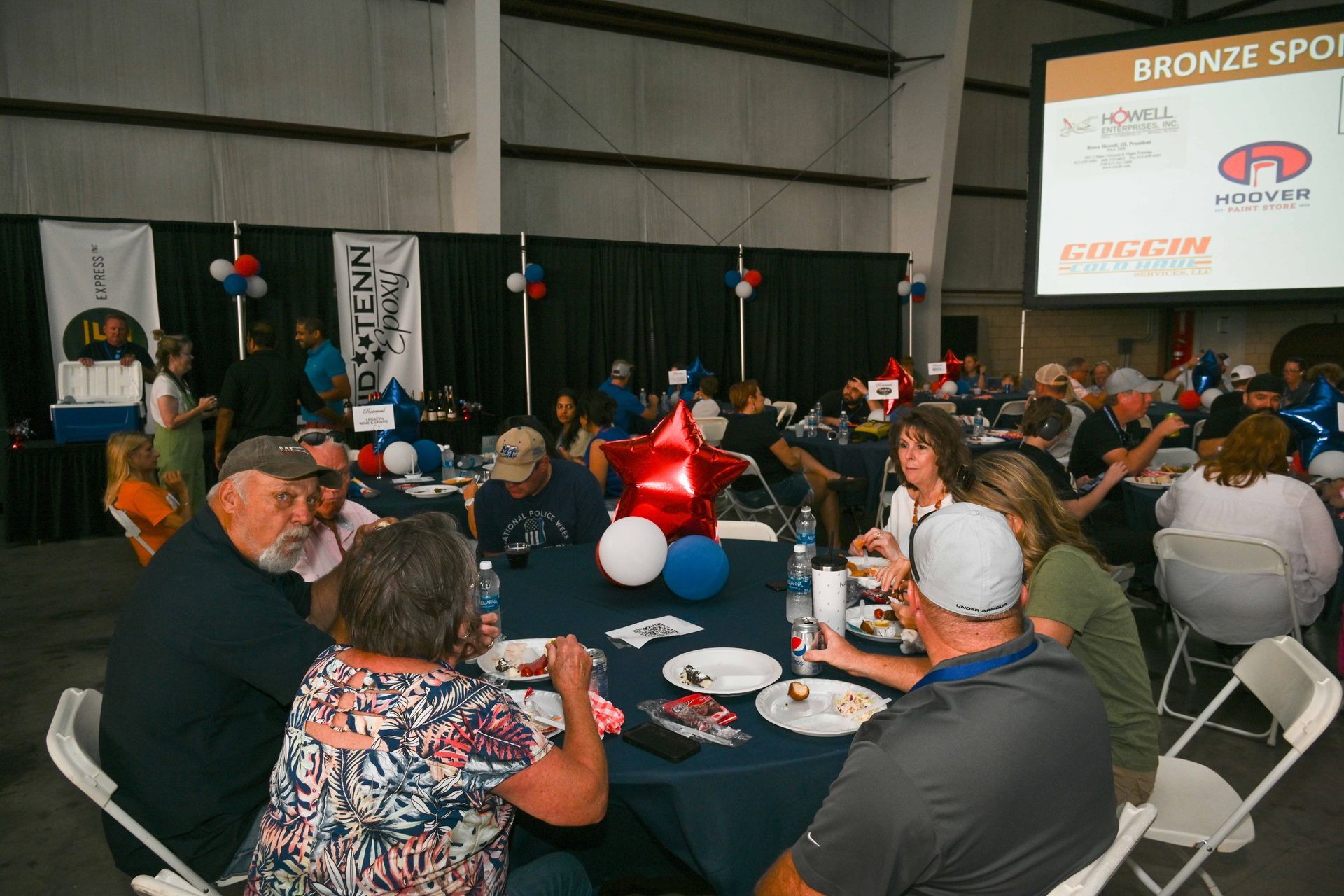 A group of people are sitting at tables in a room eating food.
