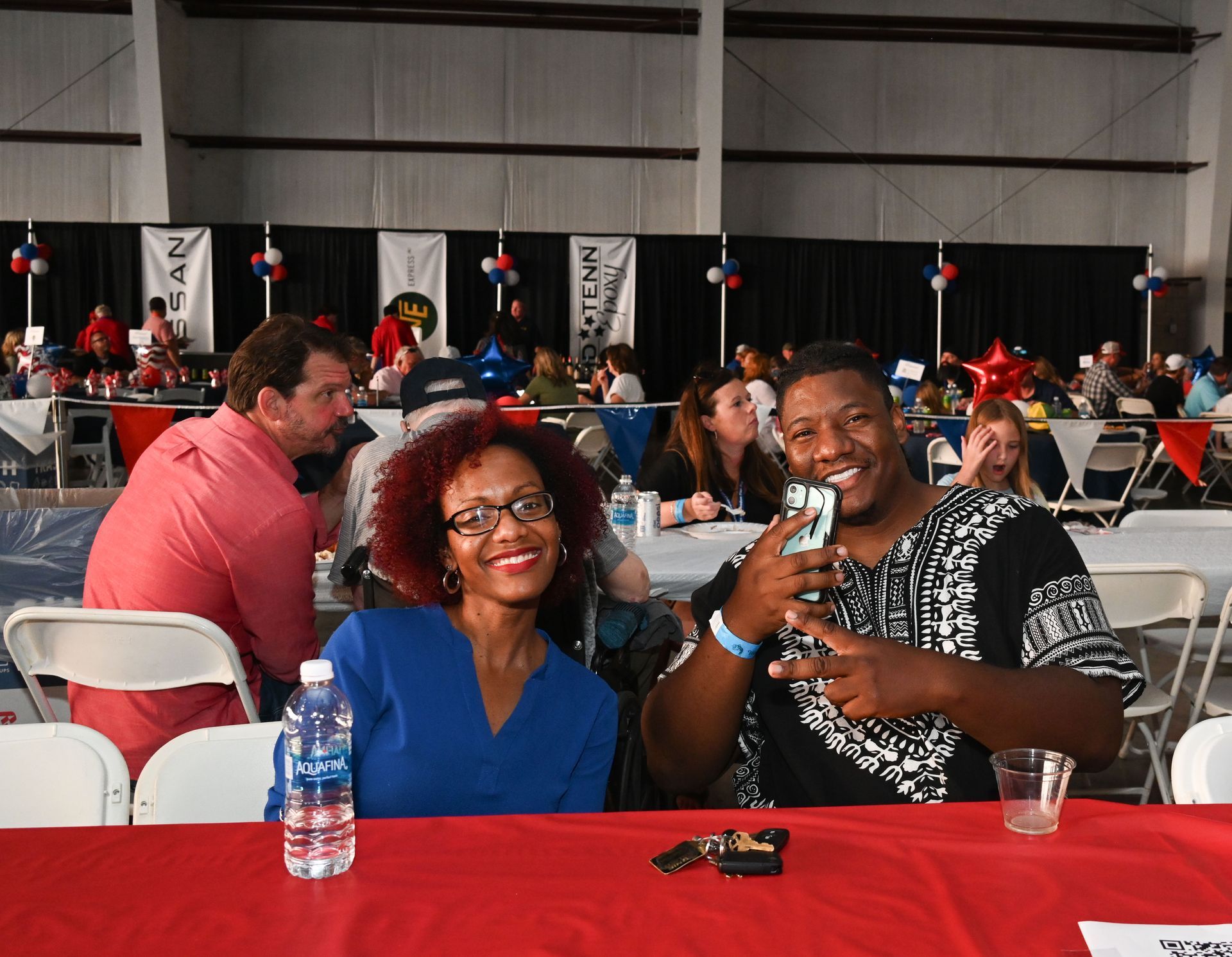 A man and a woman are sitting at a table with a red table cloth.