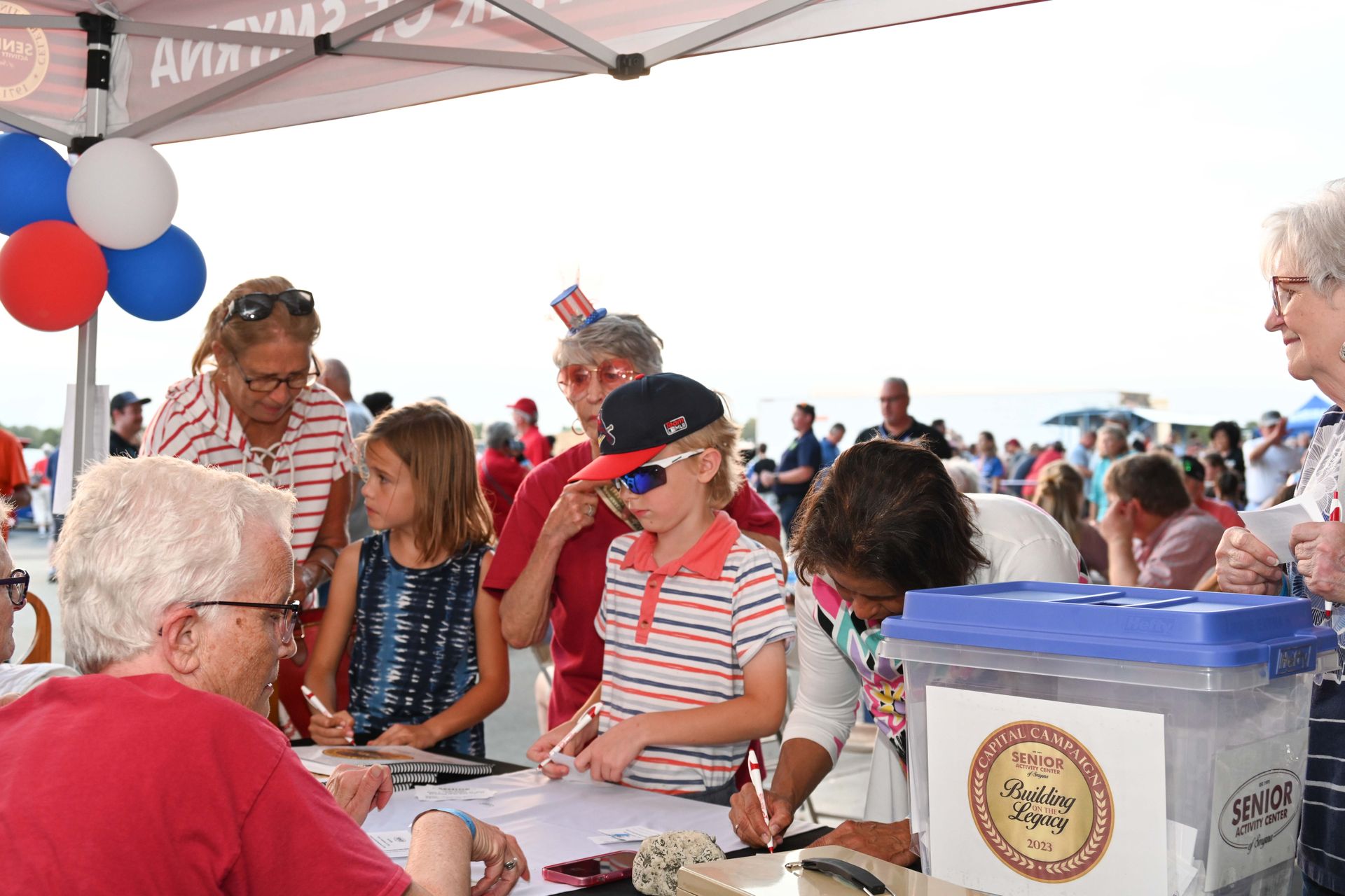 A group of people are standing around a table under a tent.