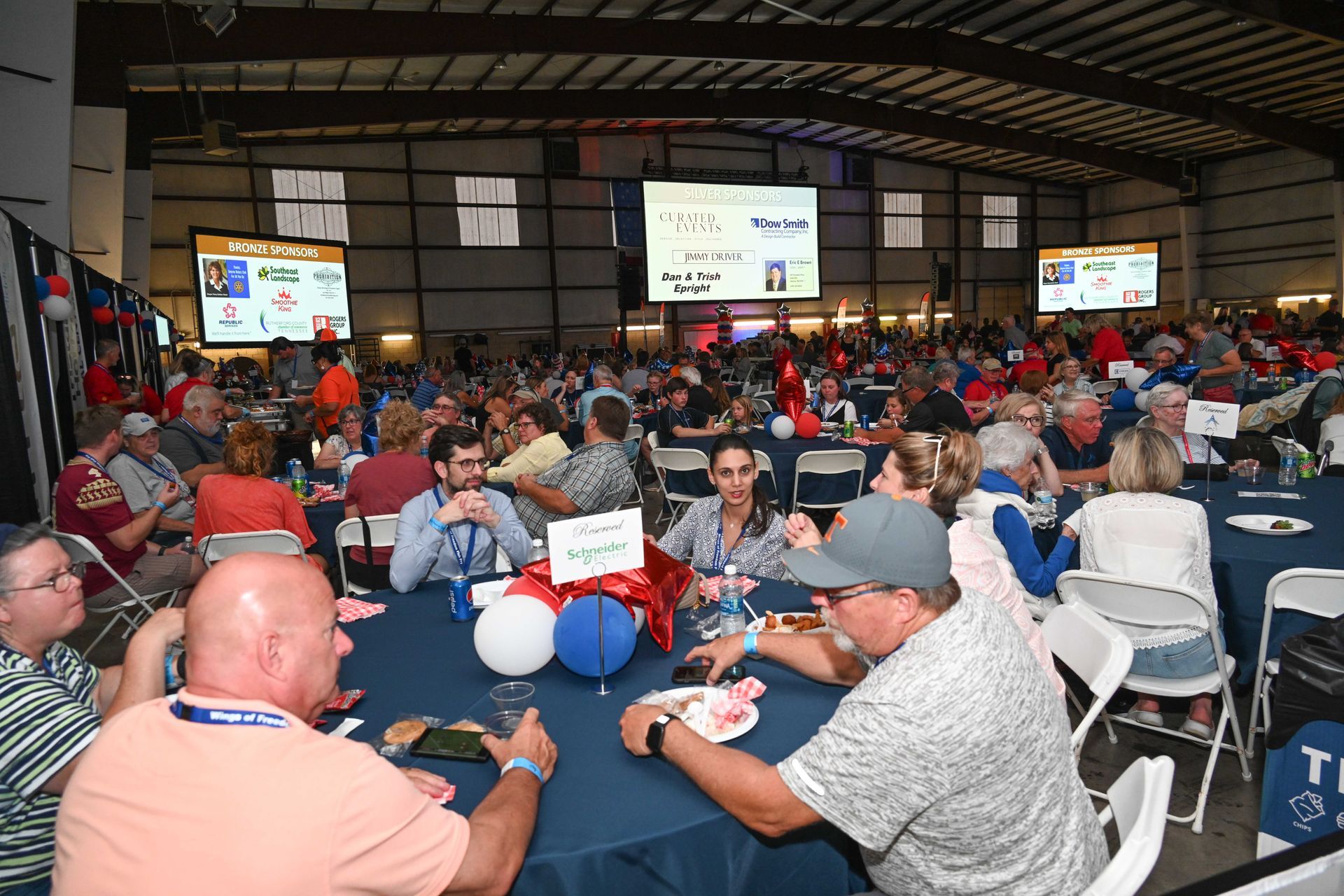 A large group of people are sitting at tables in a large room.
