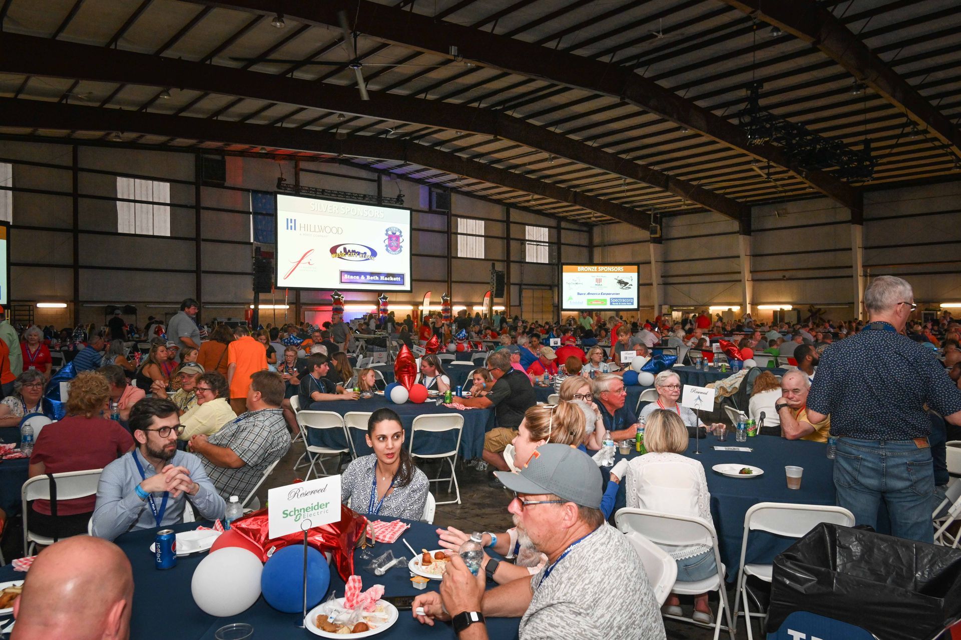 A large group of people are sitting at tables in a large room.