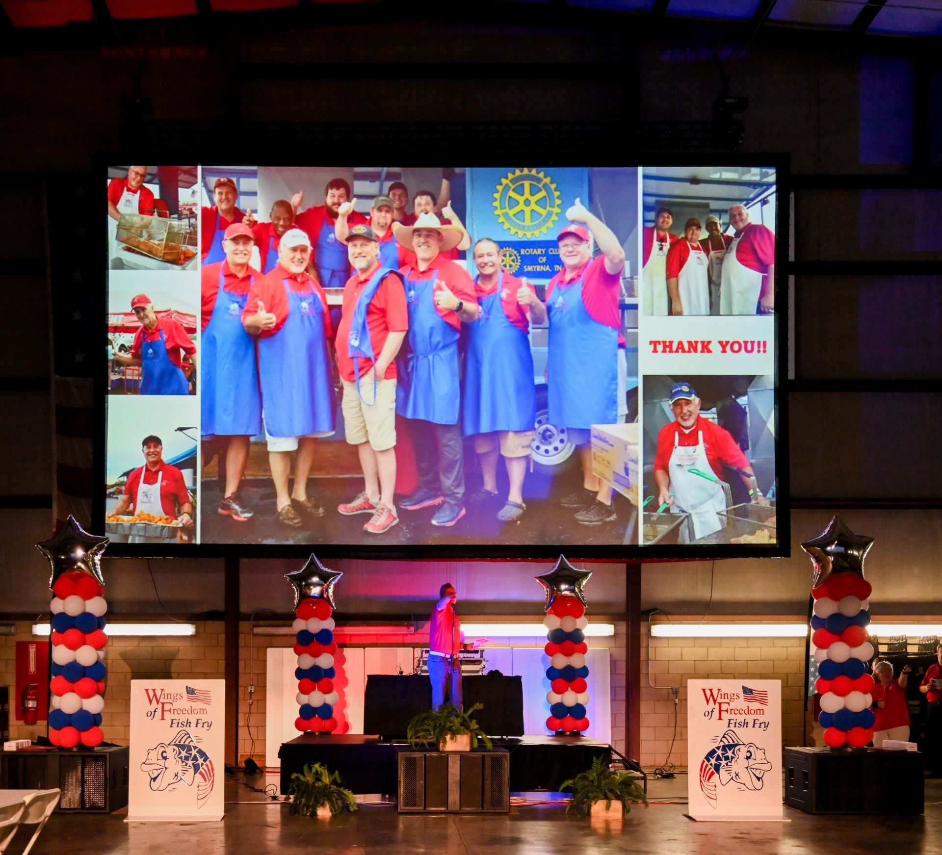 A group of people are standing in front of a large screen that says thank you