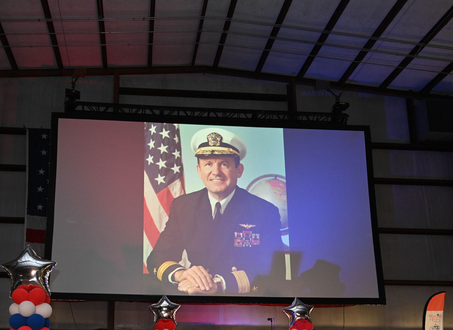 A large screen displays a picture of a man in a military uniform