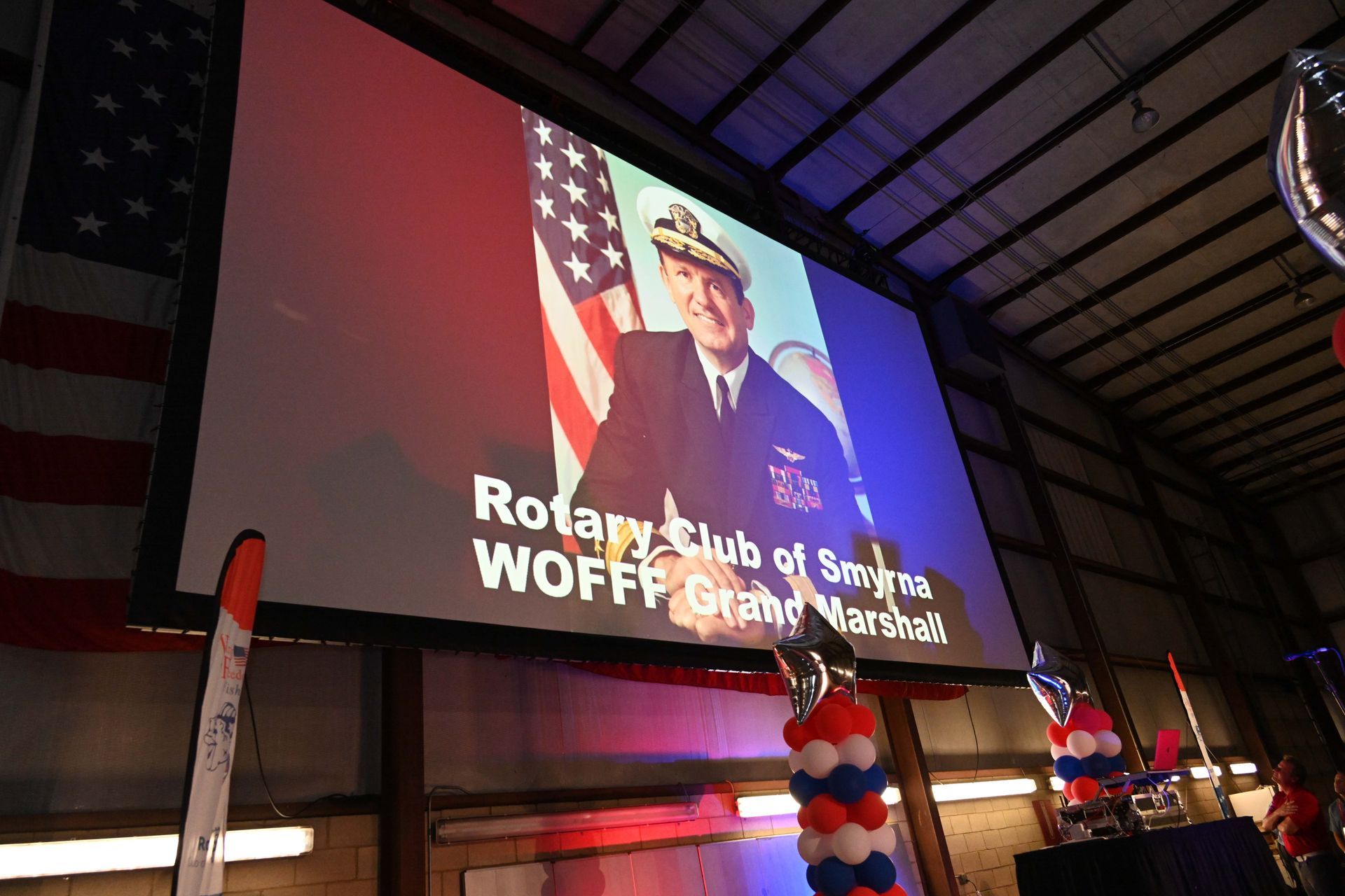 A large screen with a picture of a man and the words 