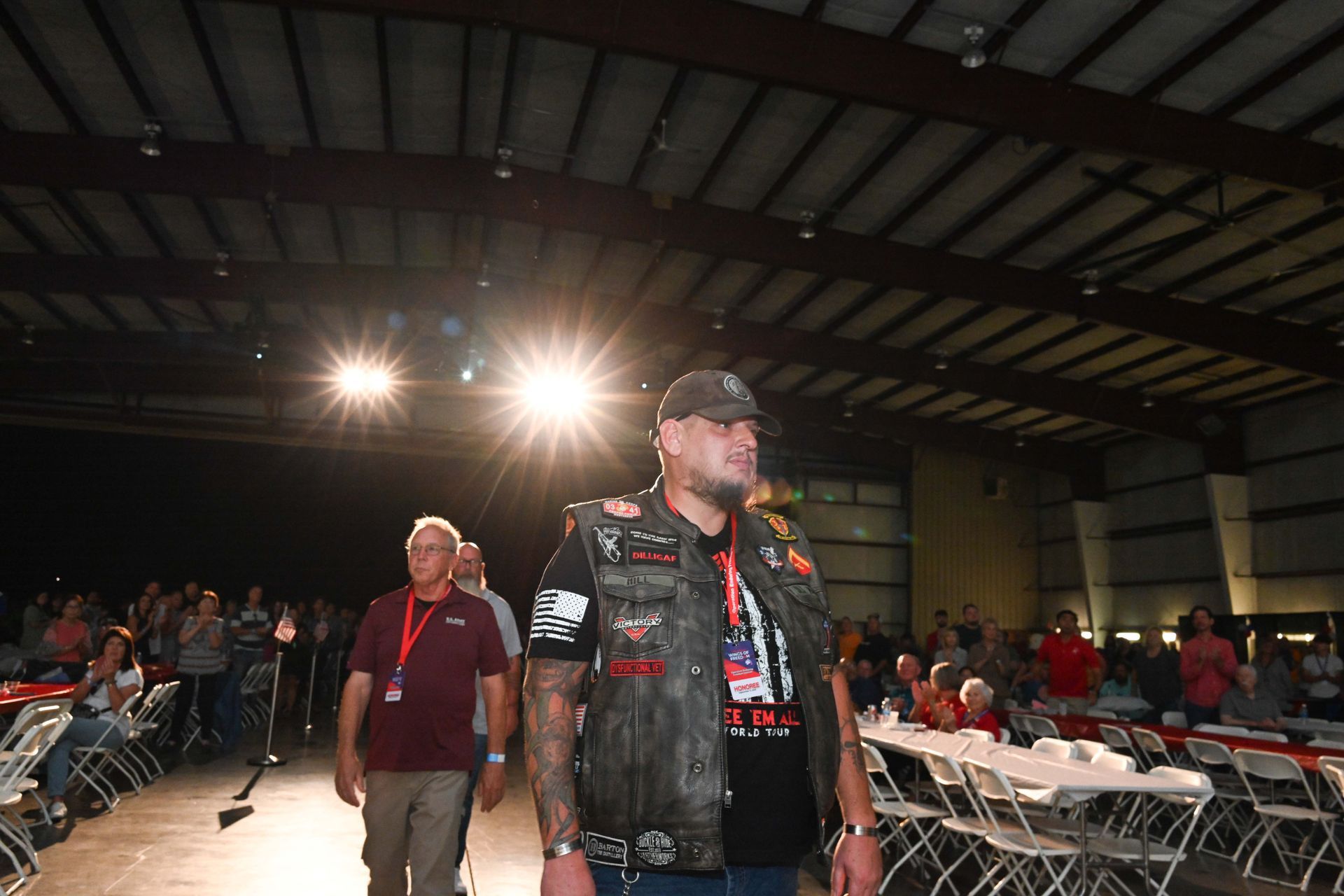 A man in a leather vest is walking in a dark room