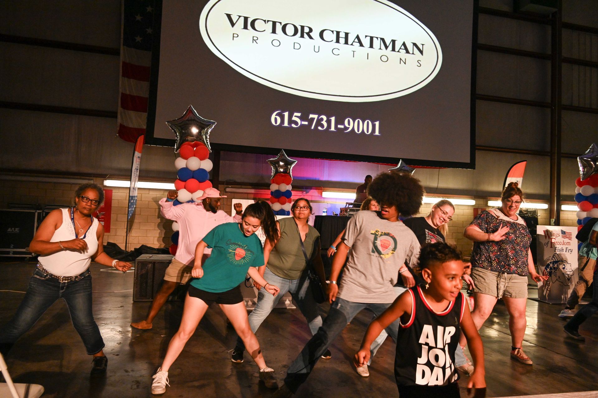 A group of people are dancing in front of a victor chatman projection screen