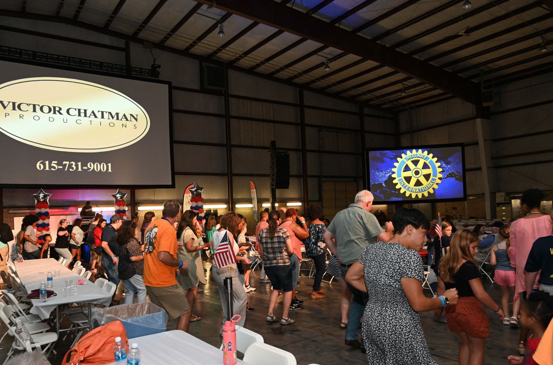 A group of people are dancing in front of a large screen that says victor chatman