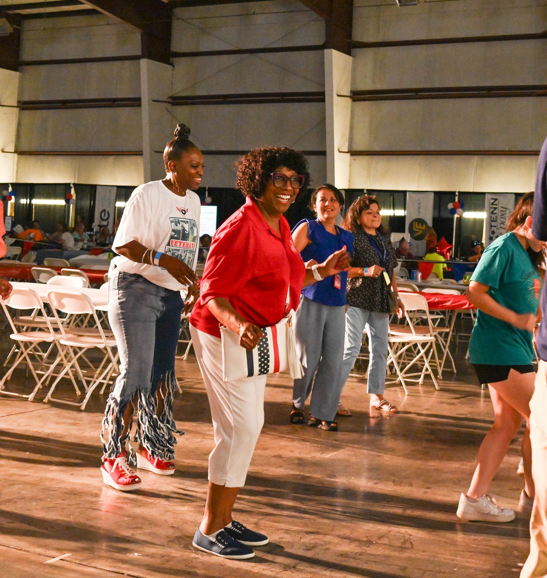 A woman in a red shirt is dancing with other people