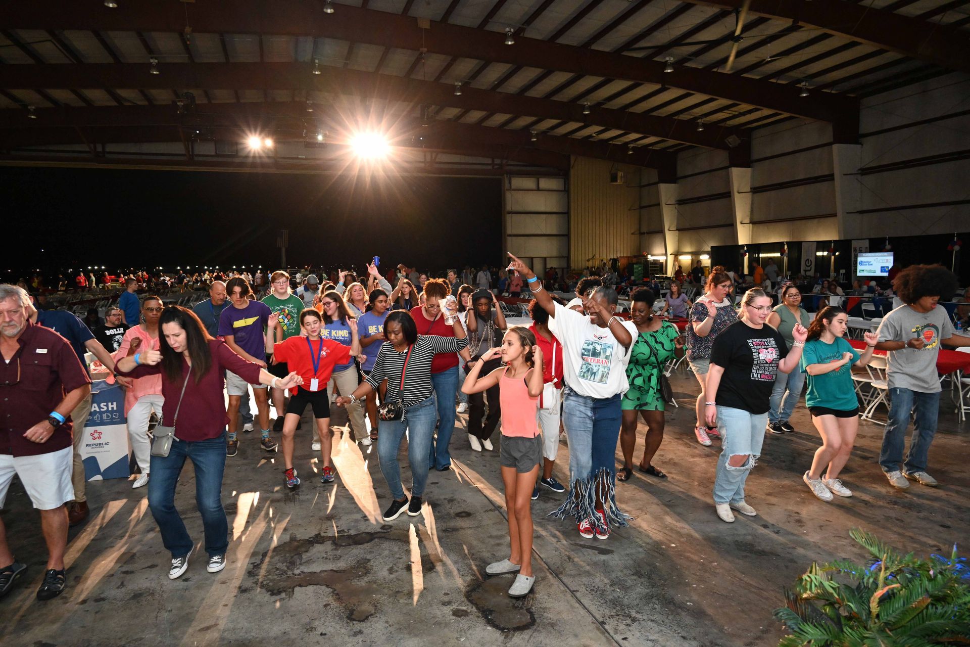 A large group of people are dancing in a large room.