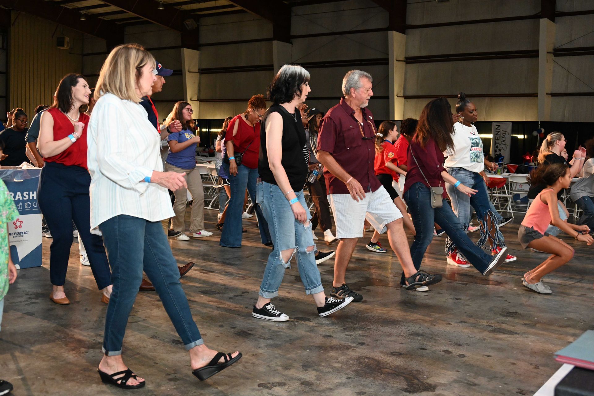 A group of people are dancing in a warehouse.