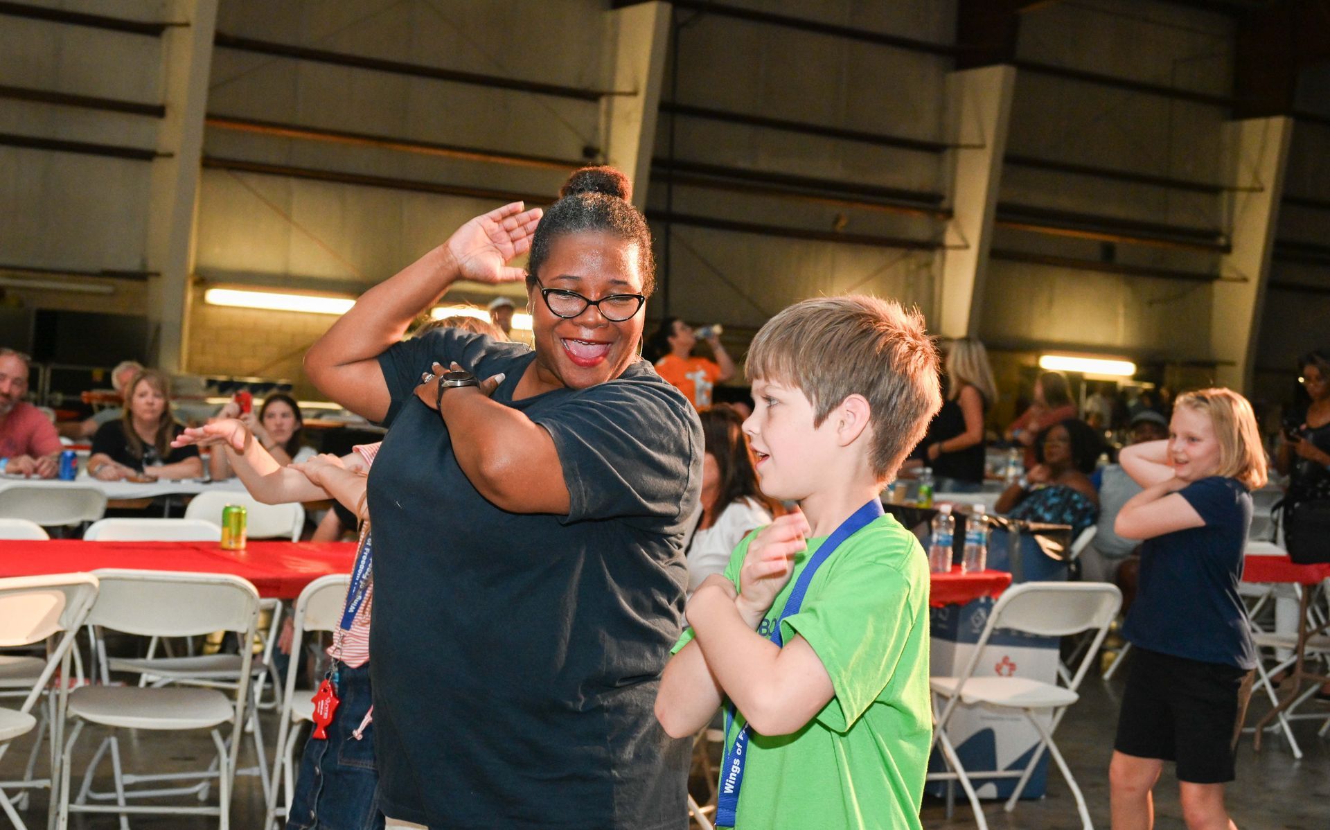A woman and a boy are dancing in a crowded room.